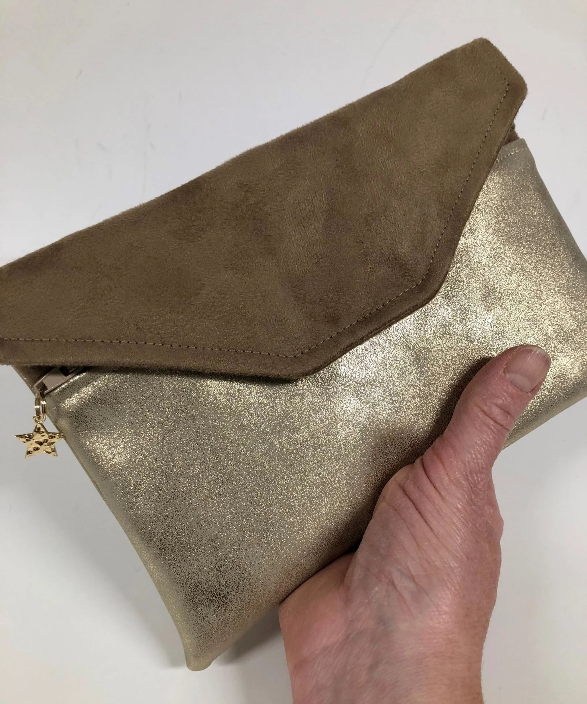 Le compagnon de sac beige et doré, porté à la main.