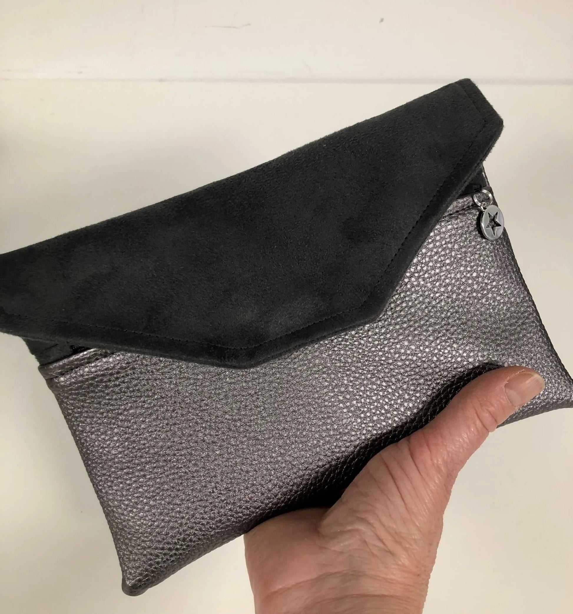 Le compagnon de sac gris irisé tenu en main.