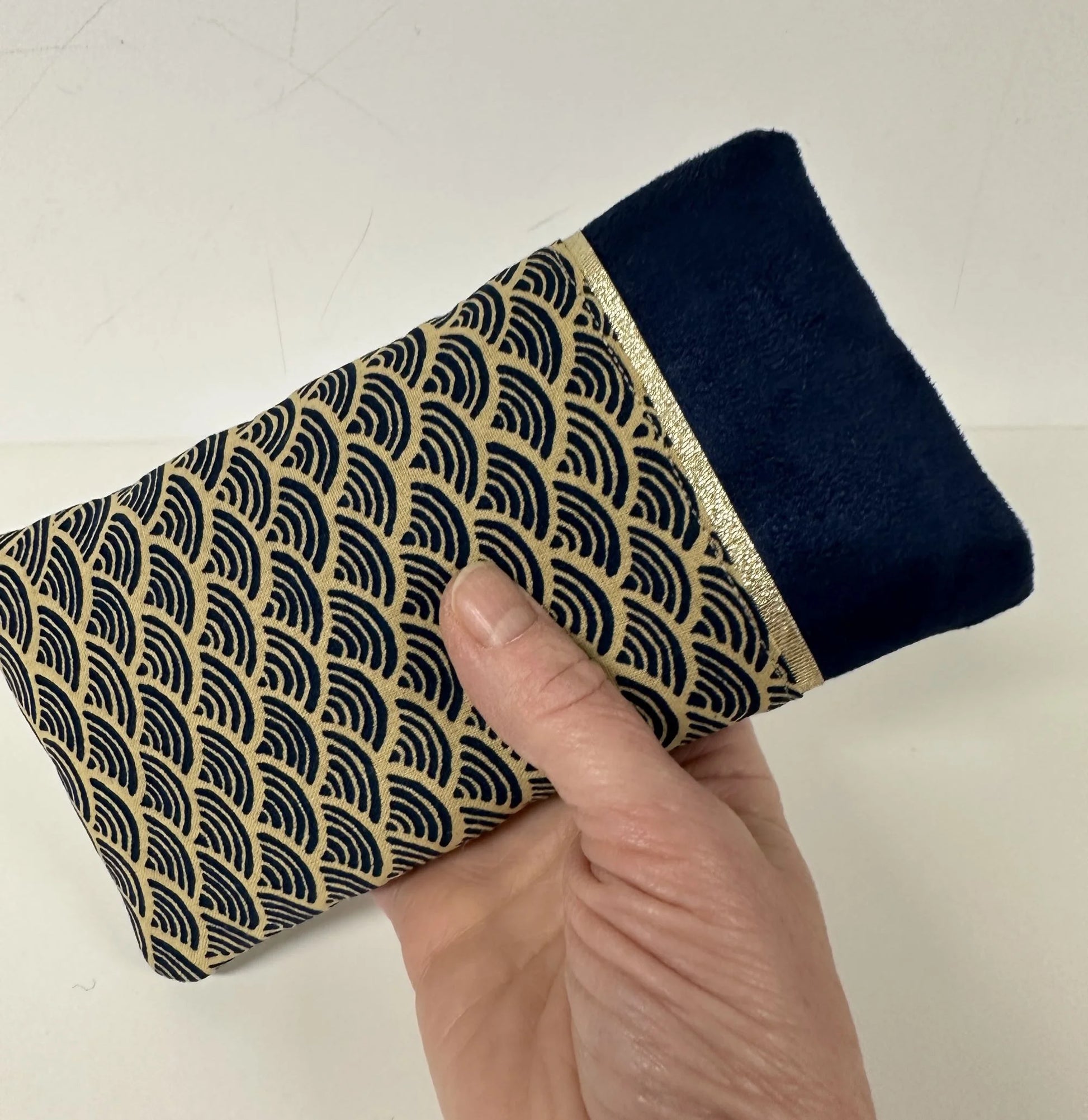 L'étui à lunettes bleu marine en tissu japonais Seigaiha, tenu en main.