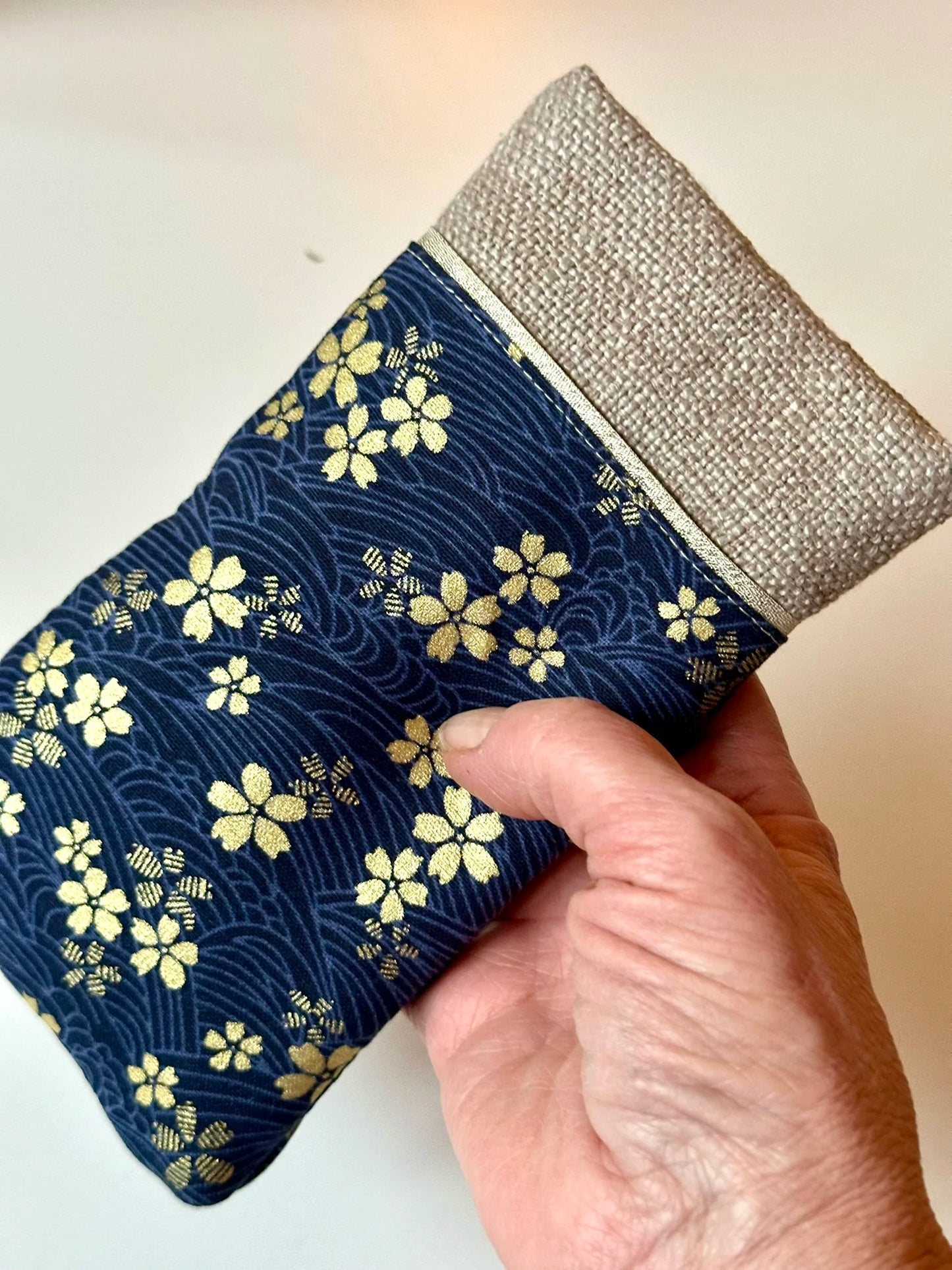 L'étui à lunettes en lin et tissu japonais Sakura bleu tenu en main.