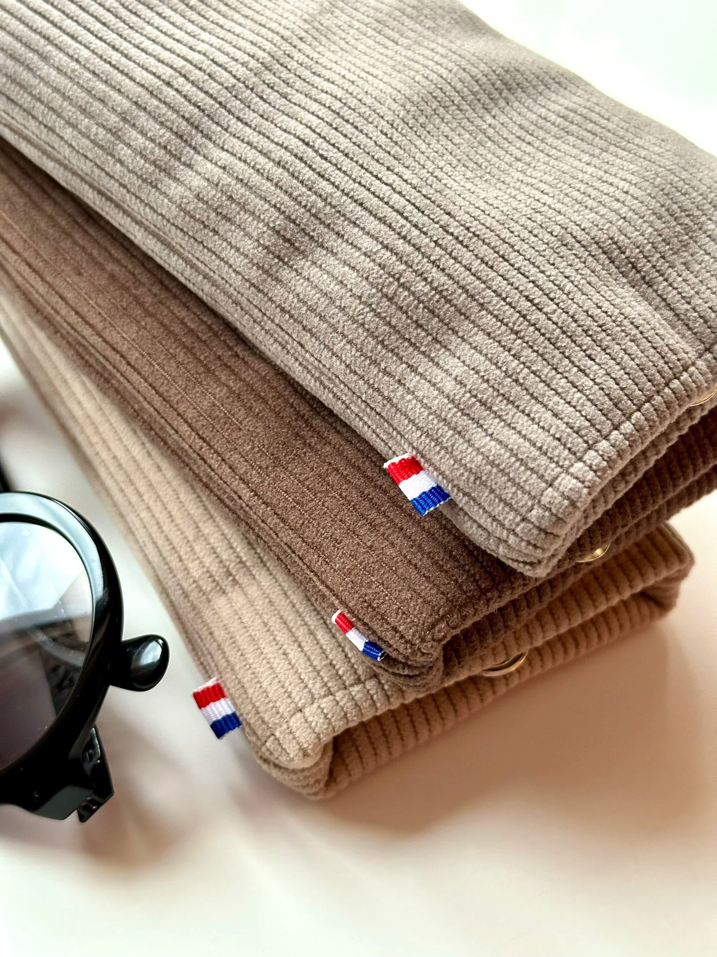L'étui à lunettes en velours cotelé beige sous le marron et le taupe.