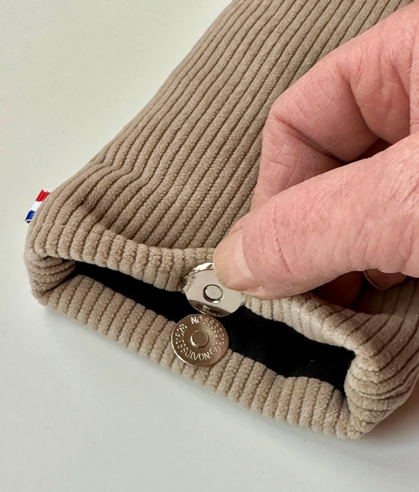 Le fermoir magnétique de l'étui à lunettes en velours cotelé beige.