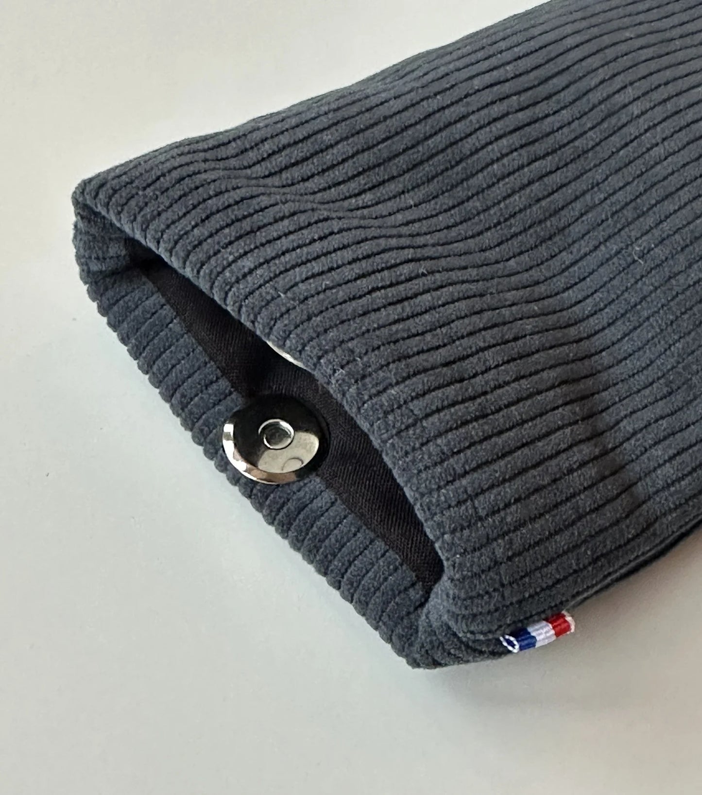 Le fermoir magnétique de l'étui à lunettes en velours cotelé bleu canard;