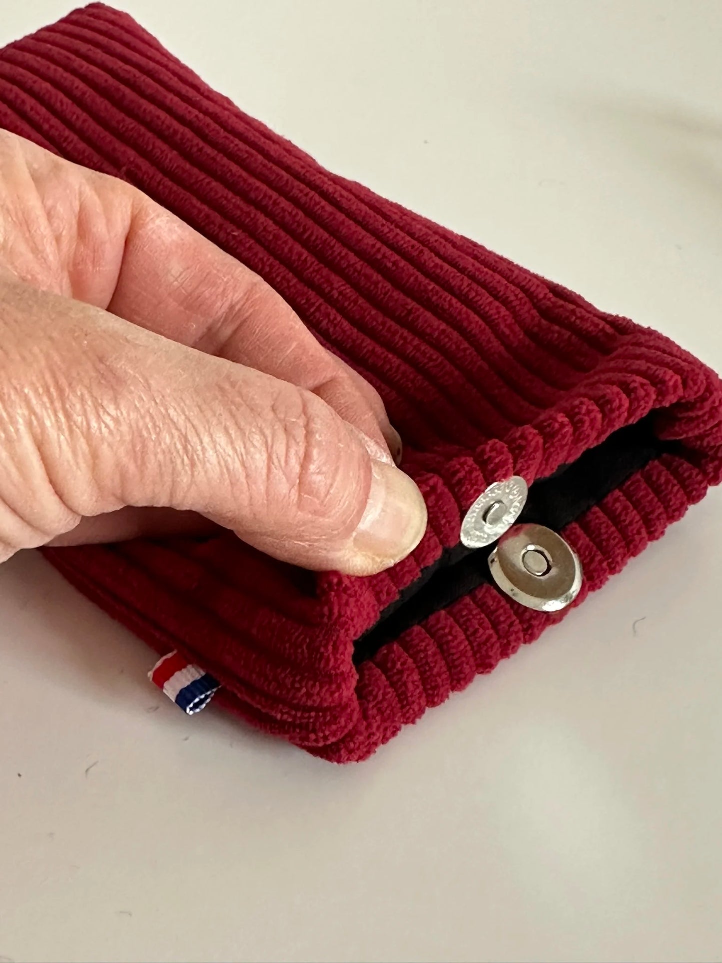 Le fermoir magnétique extra-plat de l'étui à lunettes en velours cotelé bordeaux.