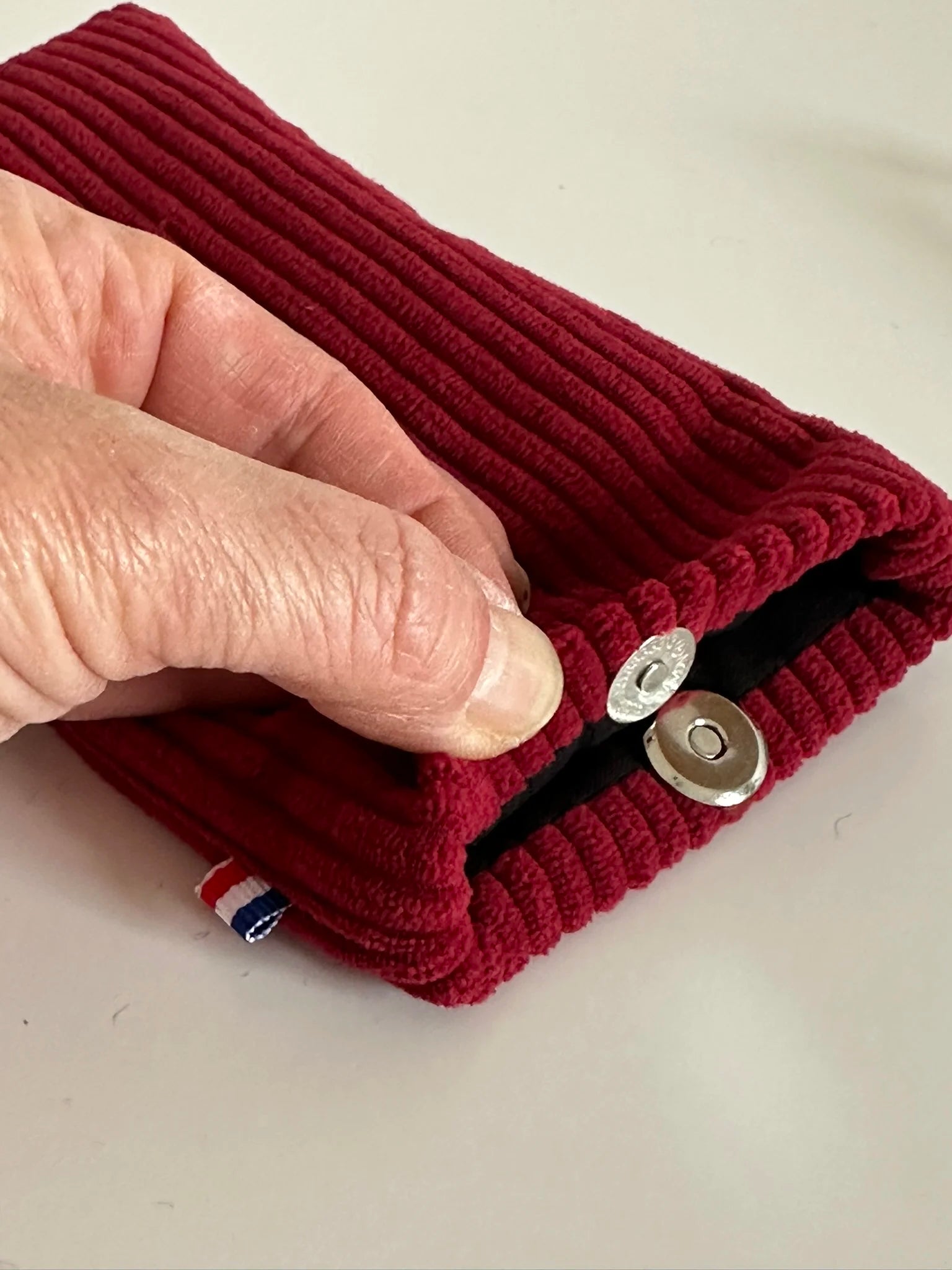 Le fermoir magnétique extra-plat de l'étui à lunettes en velours cotelé bordeaux.