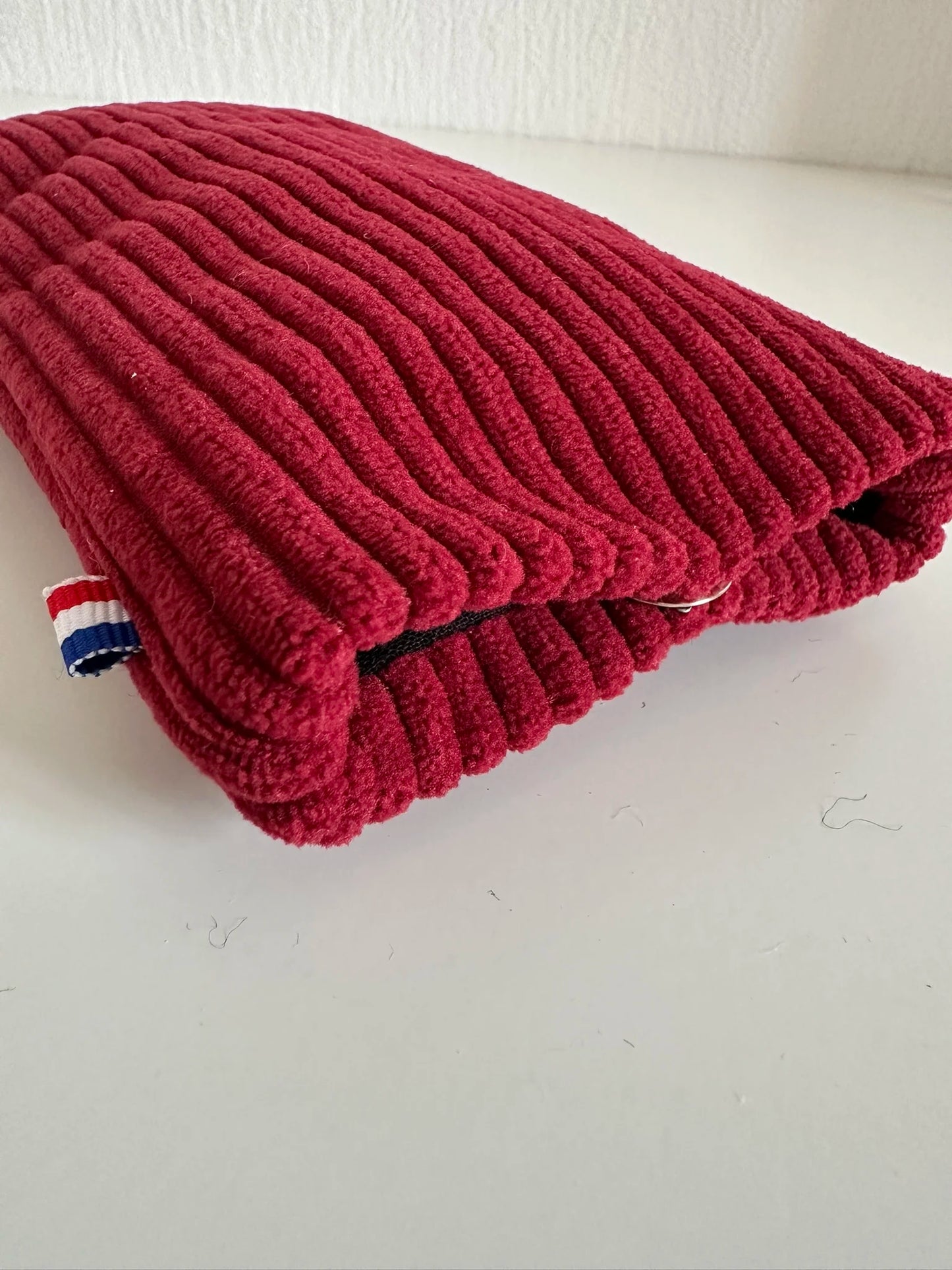 L'étui à lunettes en velours cotelé bordeaux fermé.