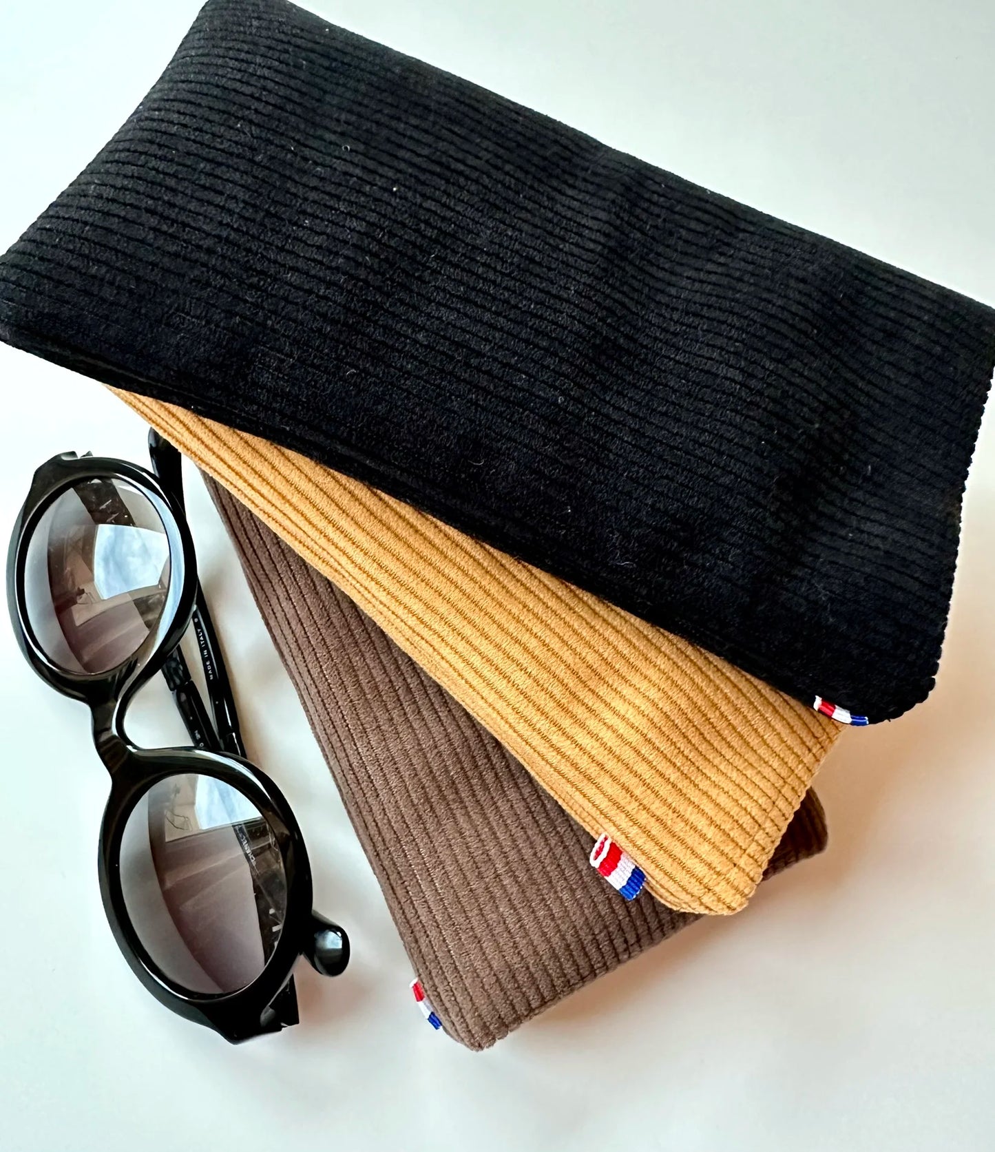 L'étui à lunettes en velours cotelé jaune moutarde, entre le marron chamois et le noir.