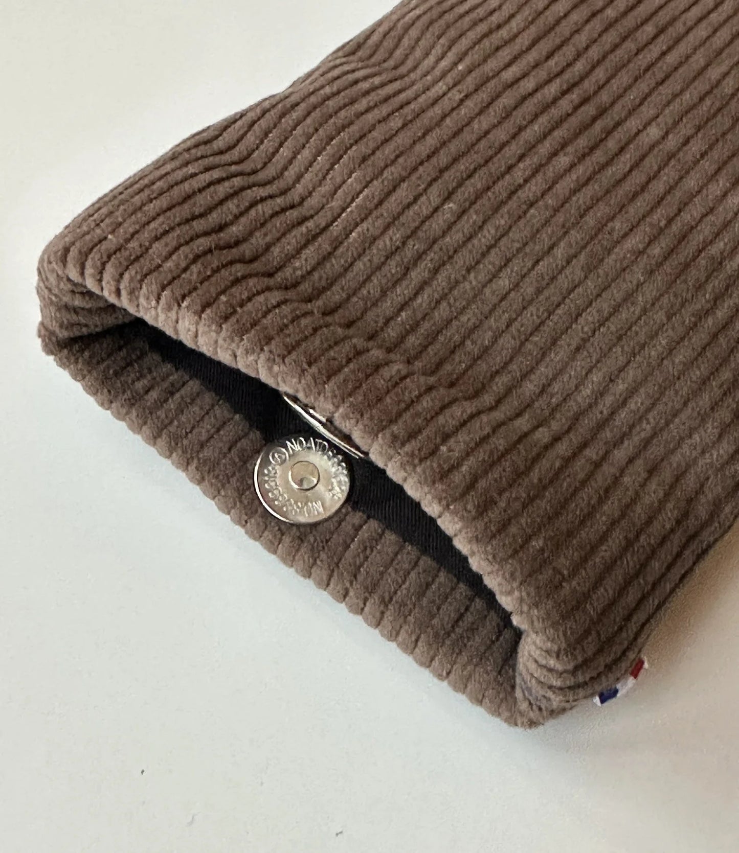 Le fermoir magnétique extra plat de l'étui à lunettes en velours cotelé marron chamois.