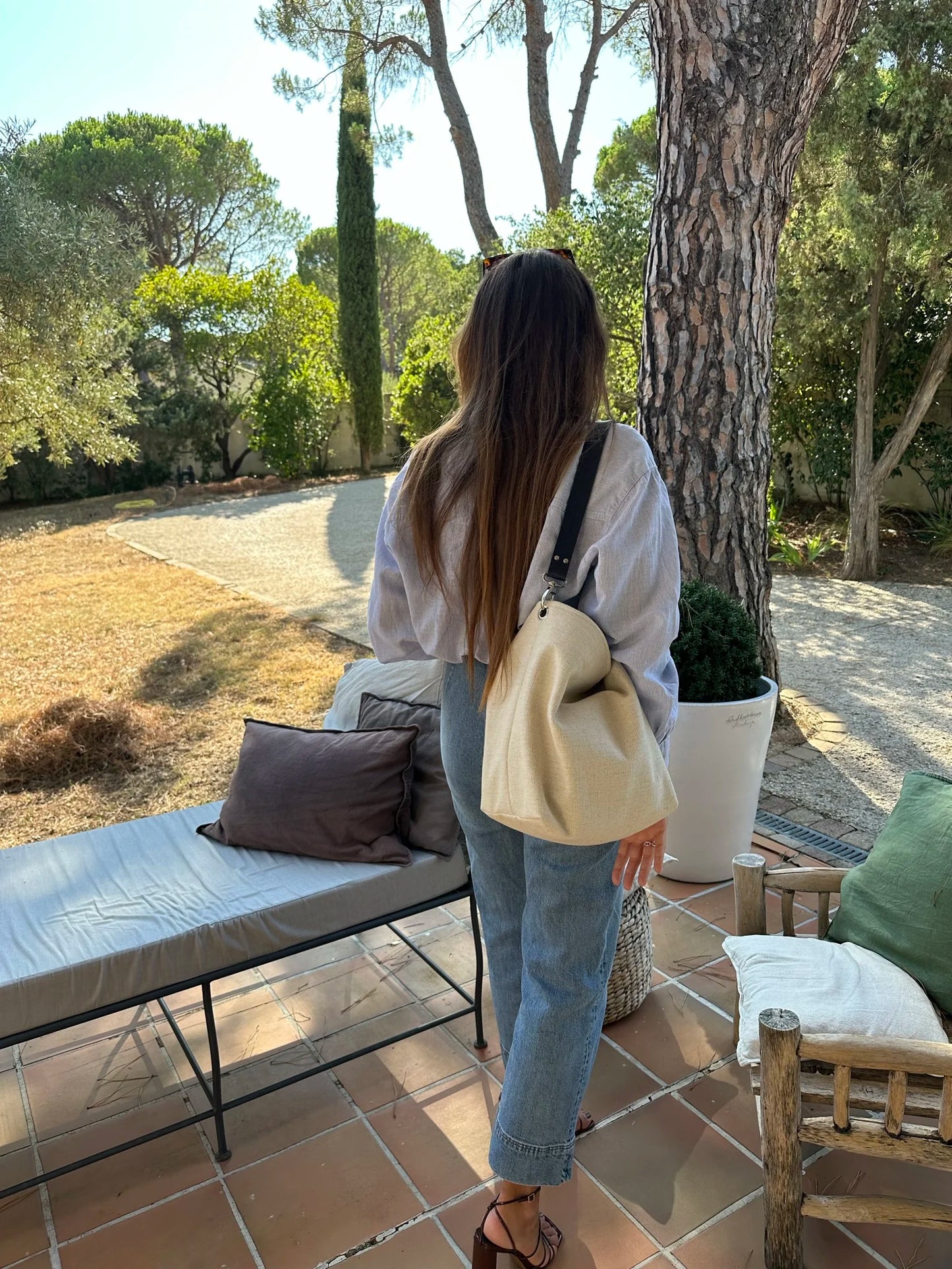 Le sac hobo en lin ivoire porté à l'épaule avec son anse en cuir bleu marine