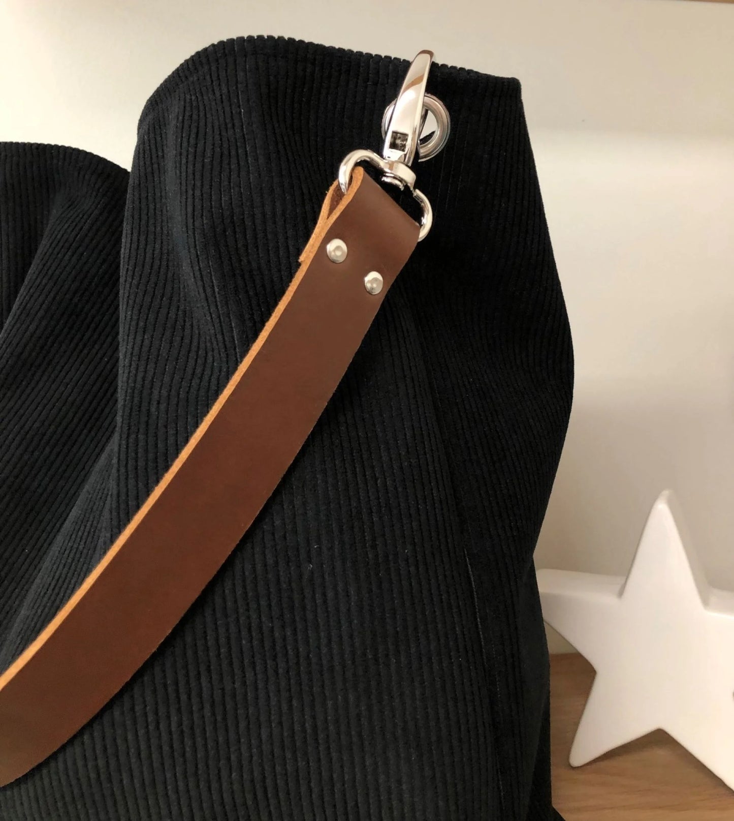 vue de détail de l'anse en cuir marron du sac hobo en velours cotelé noir