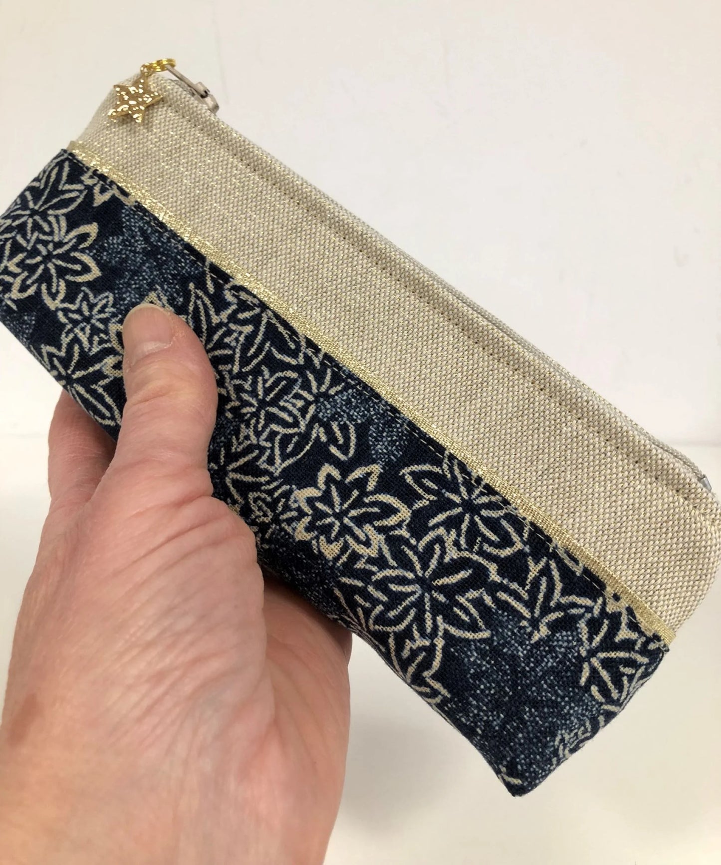 La mini-trousse à stylos en tissu japonais traditionnel bleu nuit et doré, tenue à la main.