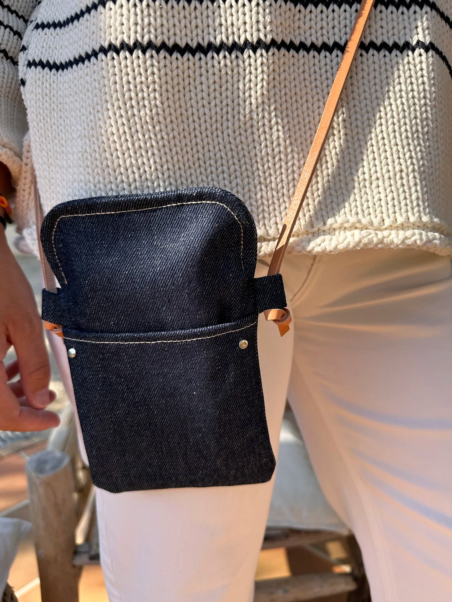Vue détaillée de la pochette bandoulière téléphone en denim et cuir naturel, portée en travers.
