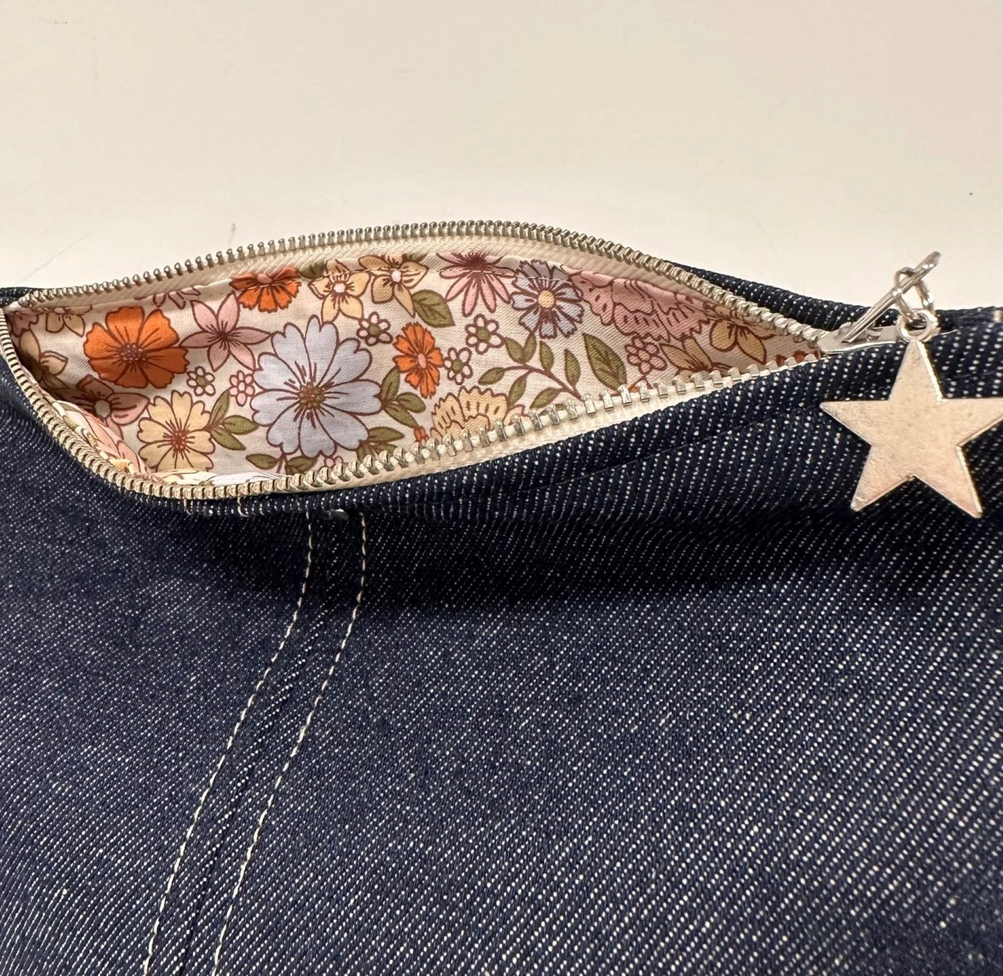 Détail de la doublure intérieure fleurie de la pochette en denim brut.