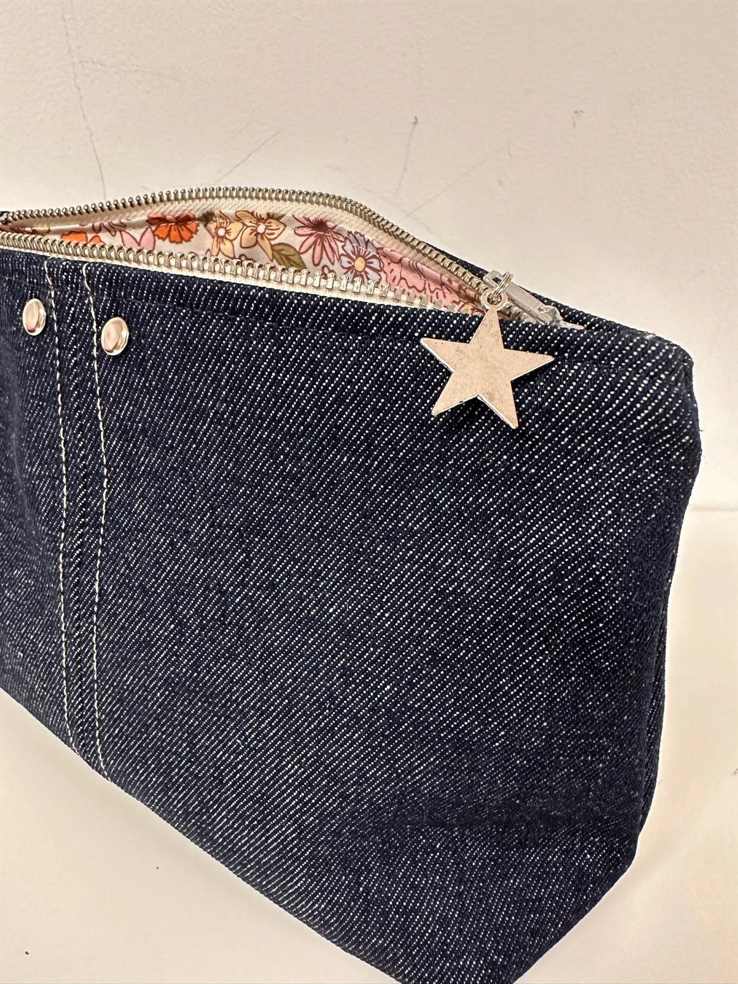 Vue détaillée de la pochette en denim brut, avec ses surpiqures contrastantes.