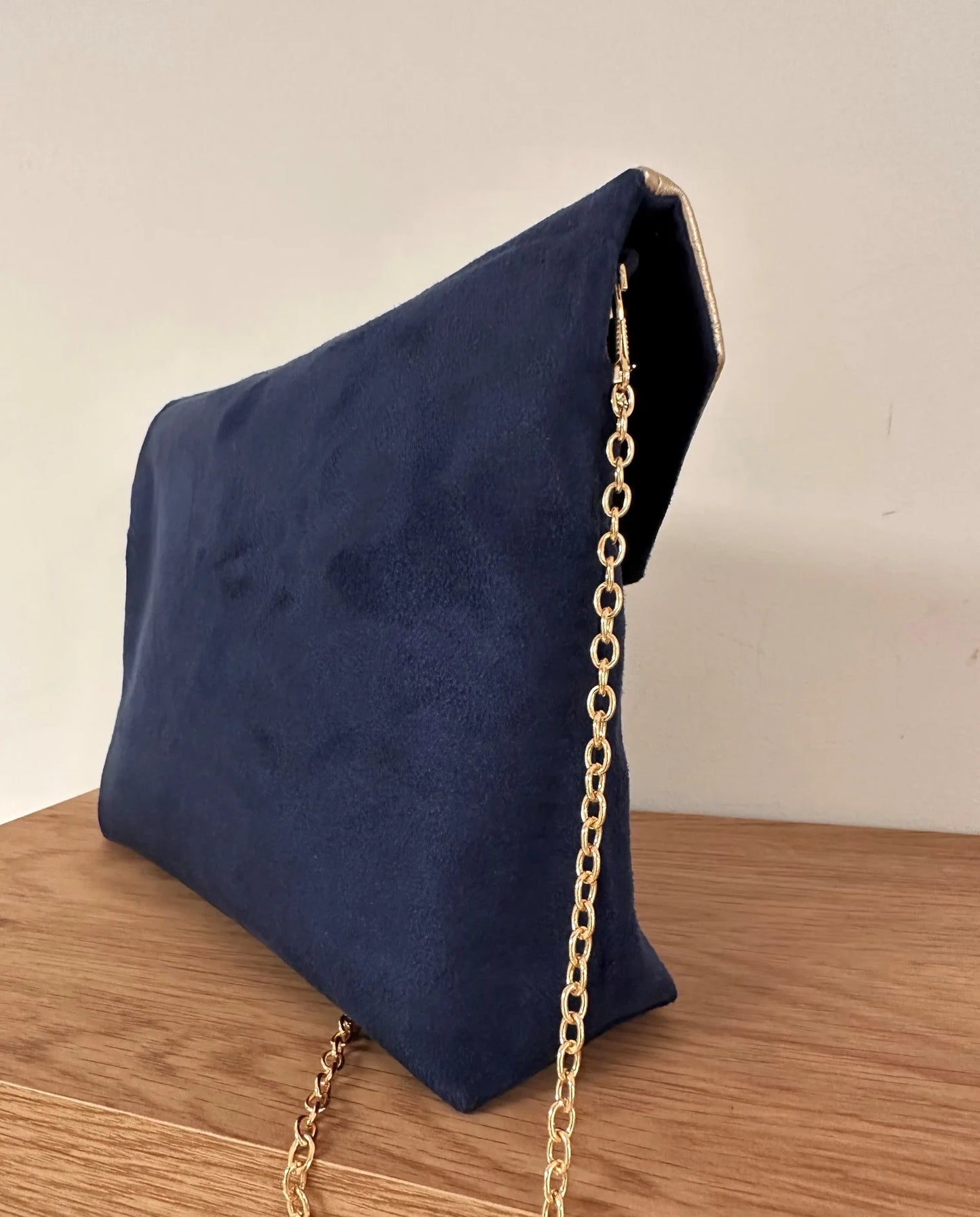 La pochette Isa zippée bleu marine et dorée vue de biais