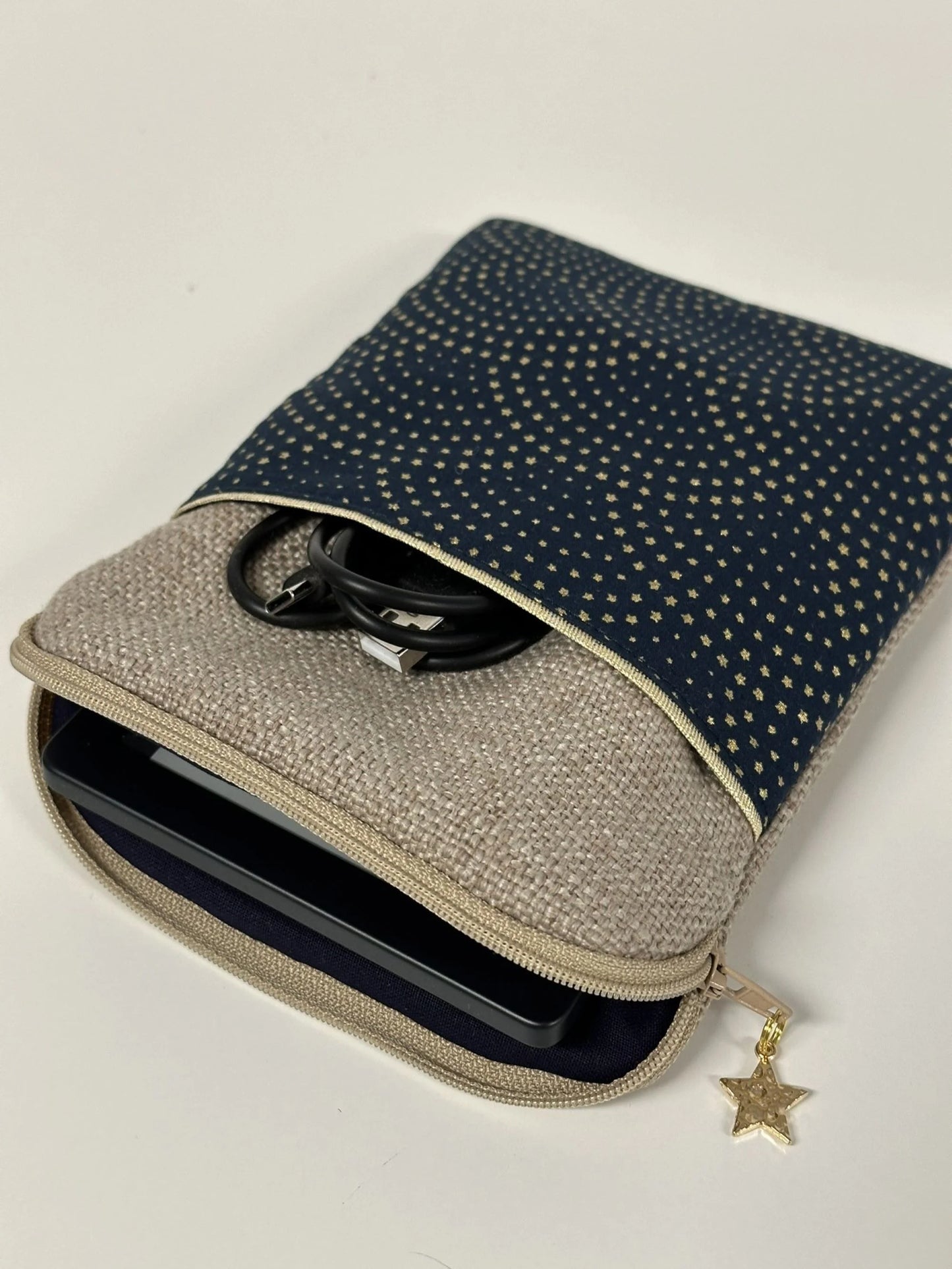 La pochette liseuse en lin et tissu bleu à étoiles dorées, entrouverte.