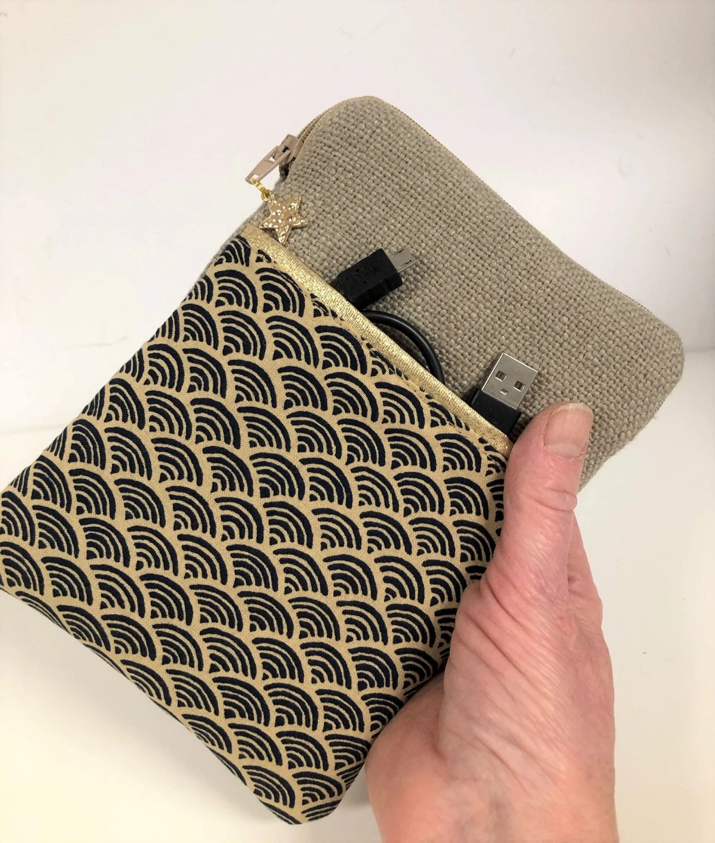 La pochette liseuse en lin et tissu japonais Seigaiha portée à la main.