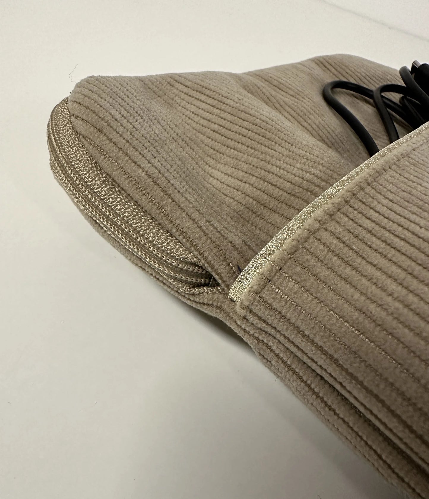 Vue détaillée de la poche avant de la pochette liseuse en velours cotelé beige.