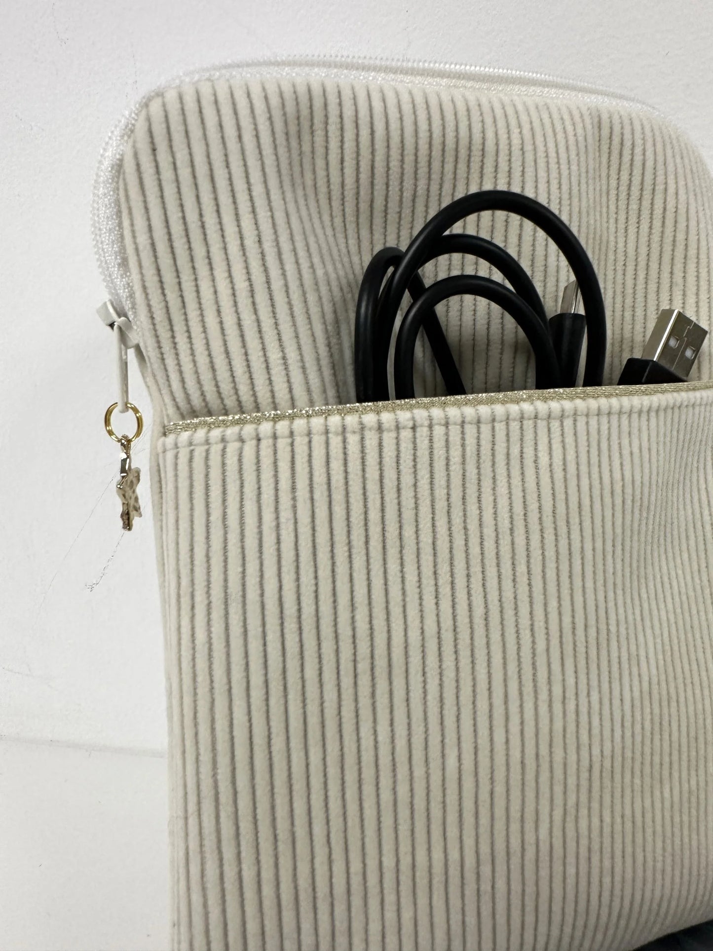 La poche avant de la pochette à liseuse en velours cotelé écru.
