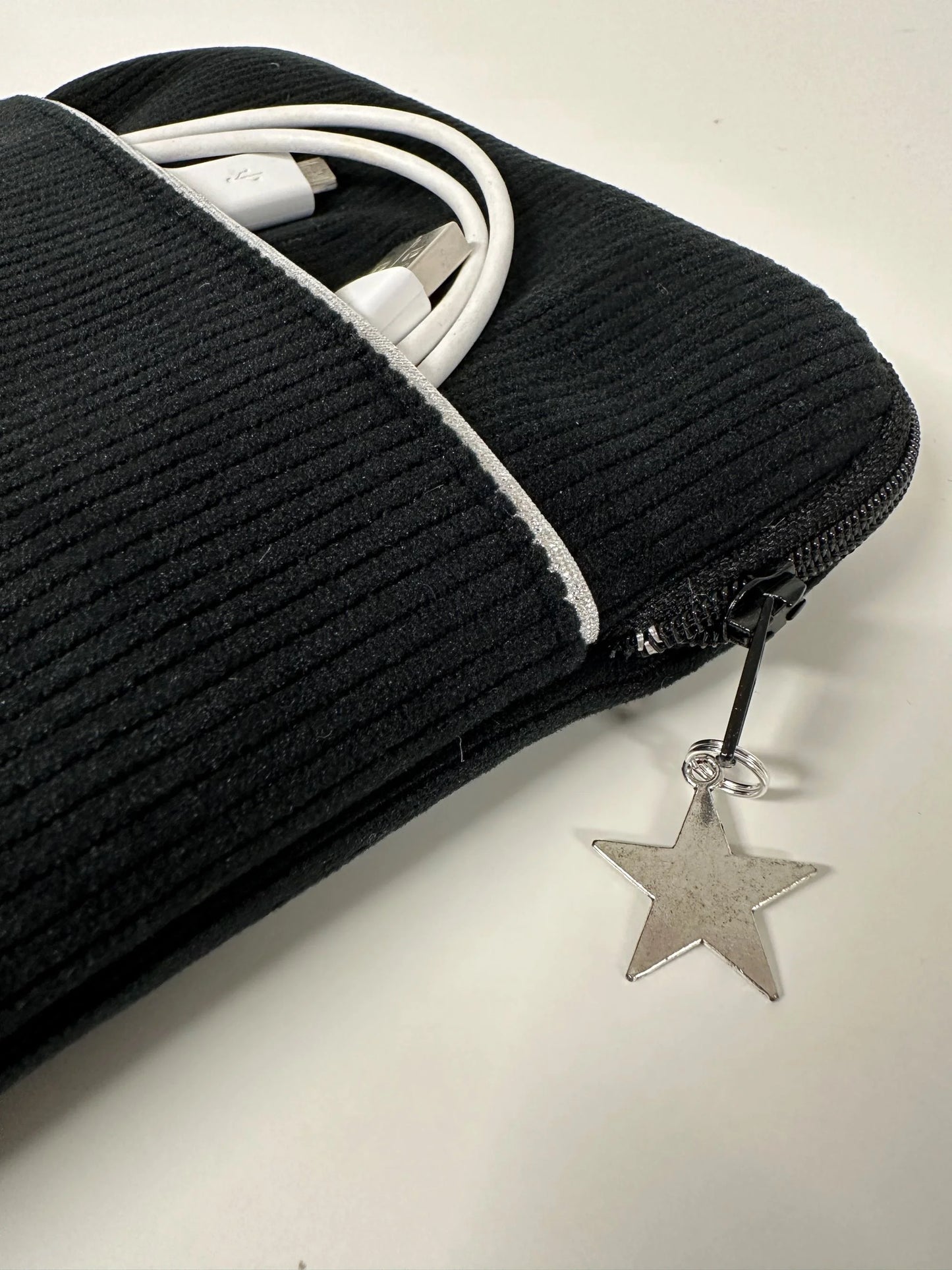 Vue détaillée de la poche avant de la pochette liseuse en velours cotelé noir.