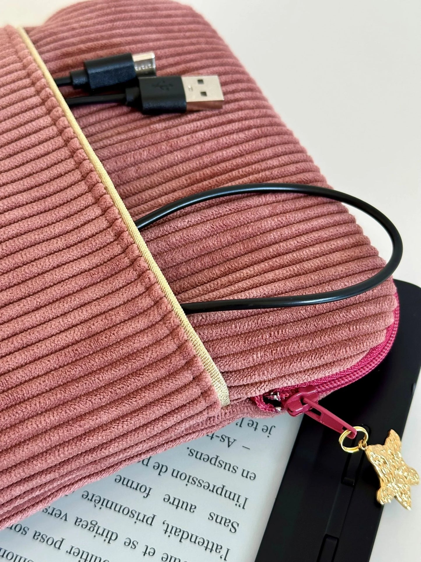 L'ouverture zippée élargie de la pochette liseuse en velours cotelé vieux rose.
