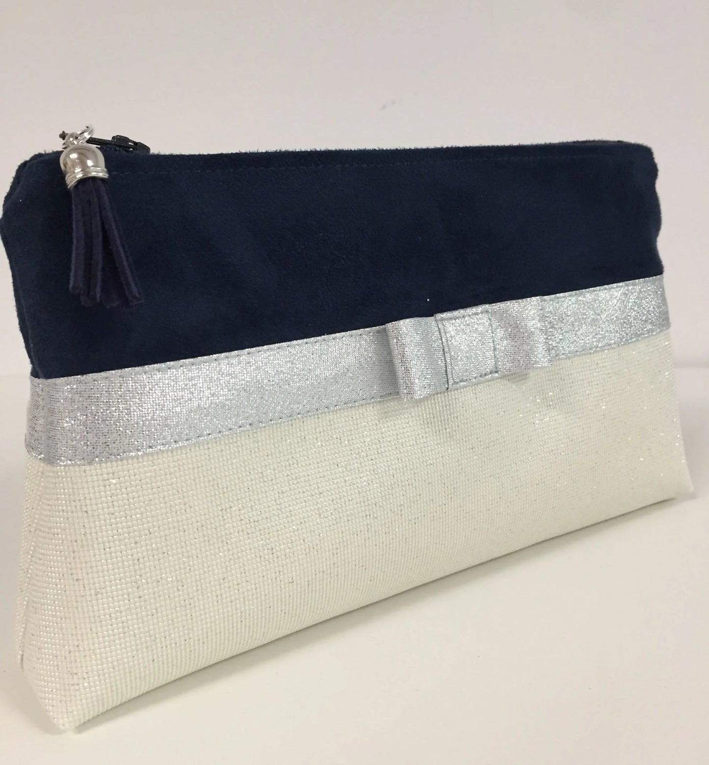 Face avant de la pochette à maquillage bleu marine et blanc à noeud argenté.