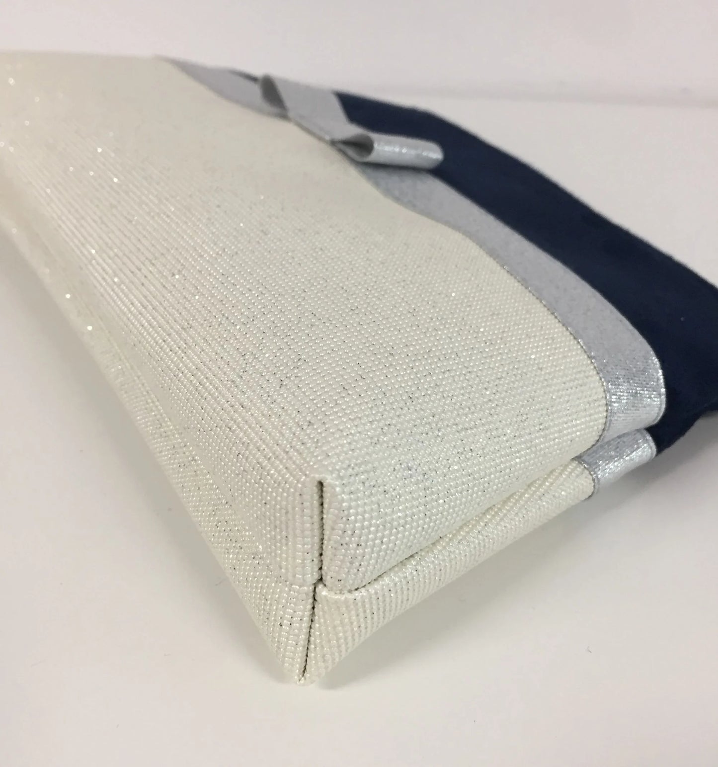 Le fond de la pochette à maquillage bleu marine et blanc à noeud argenté.