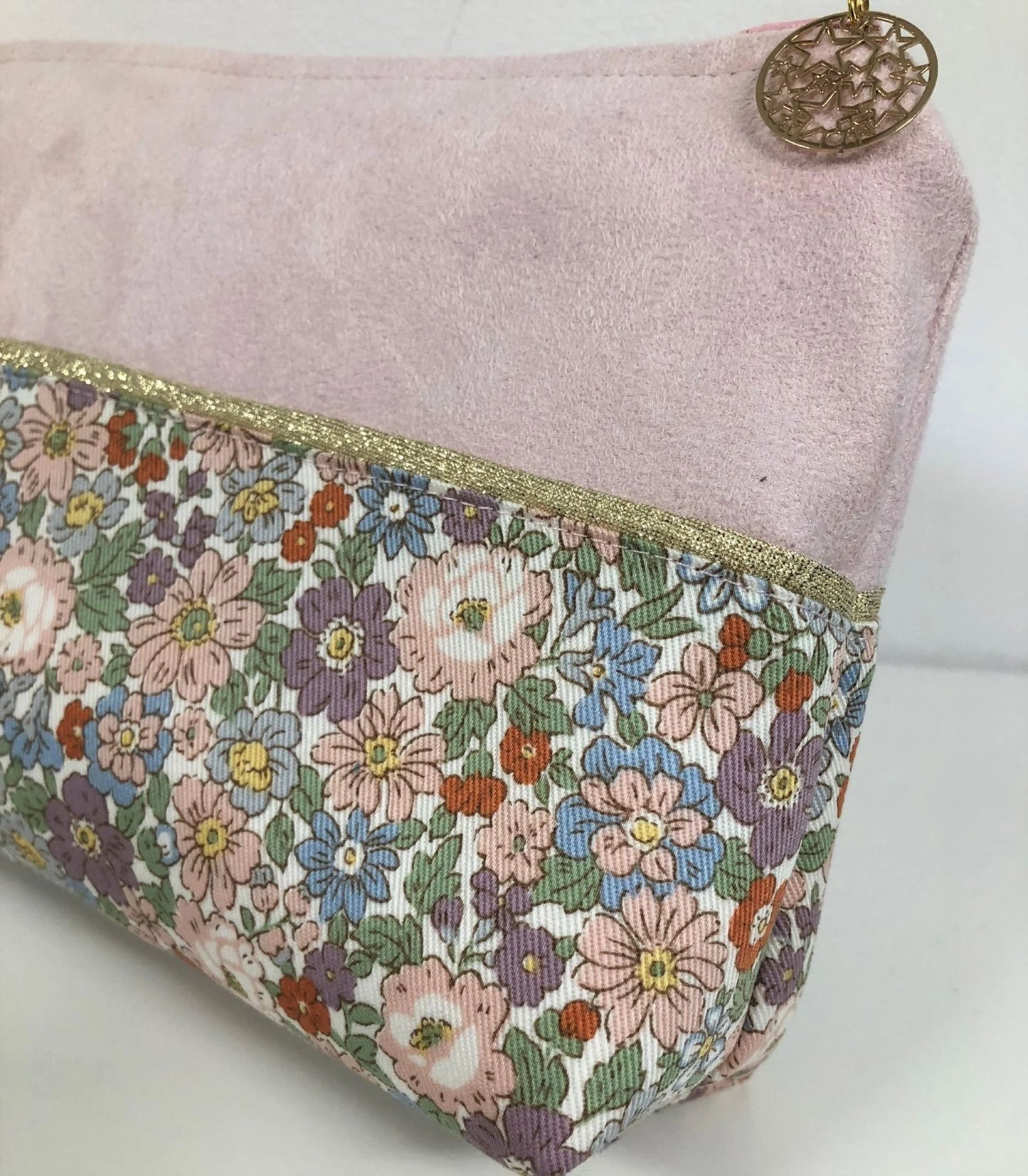 Le liseré doré de la pochette à maquillage rose et dorée à fleurs pastel.
