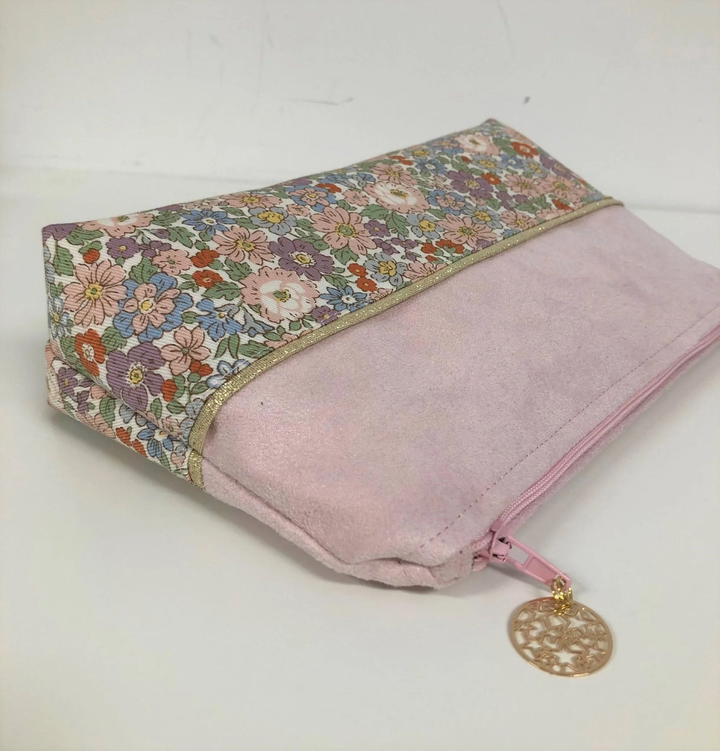 La pochette à maquillage rose et dorée à fleurs pastel, fermée.
