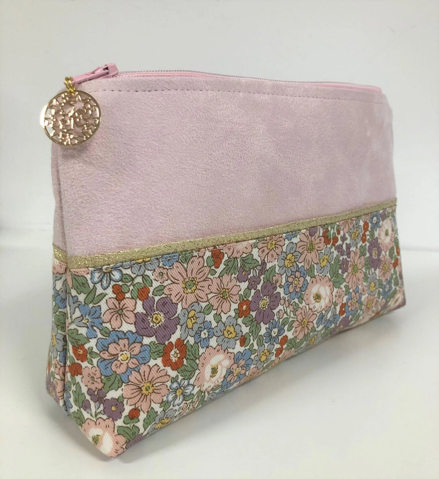 Vue latérale de la pochette à maquillage rose et dorée à fleurs pastel.