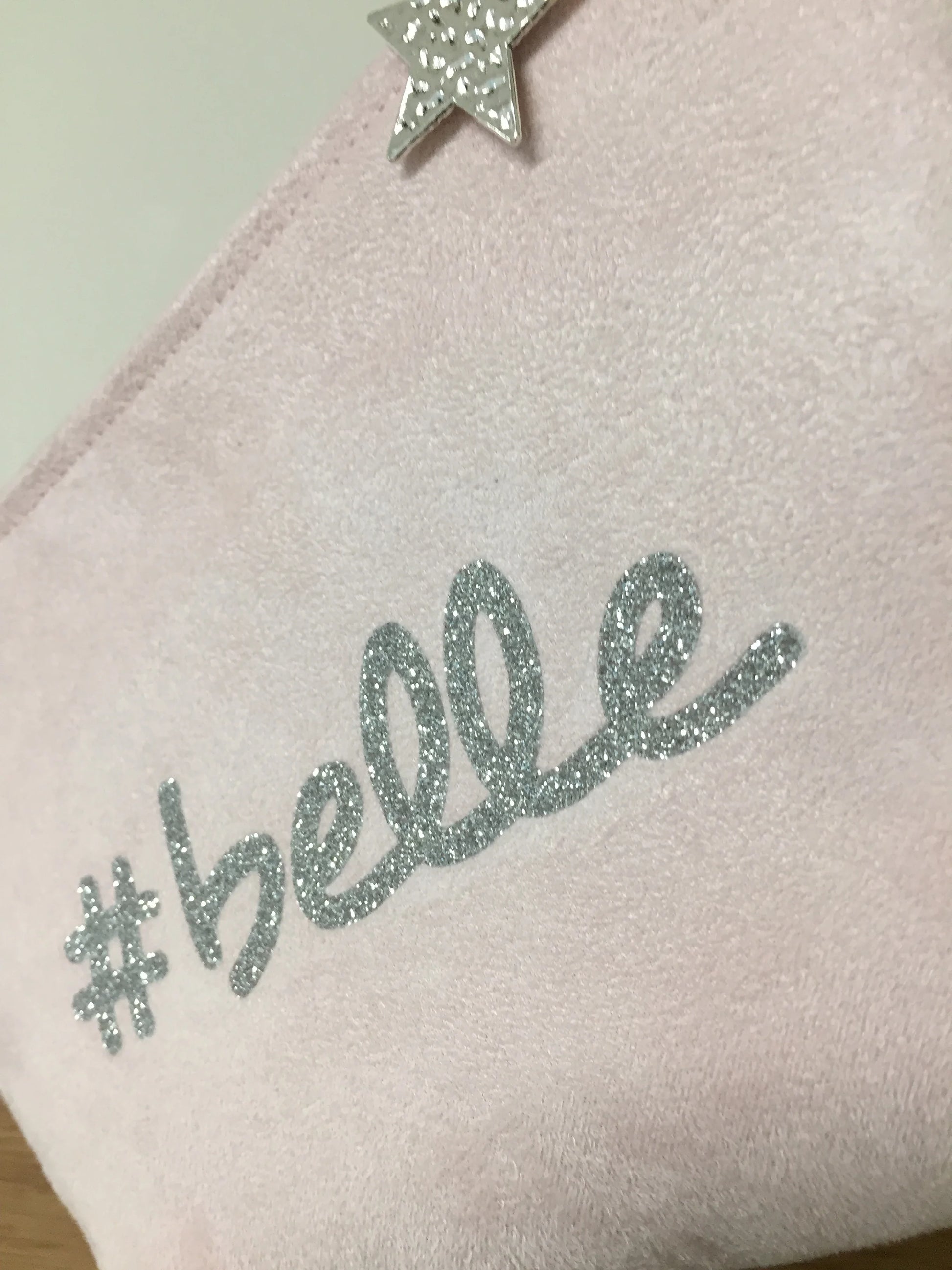Détail du flocage pailleté de la pochette à maquillage rose pastel belle à paillettes argentées.