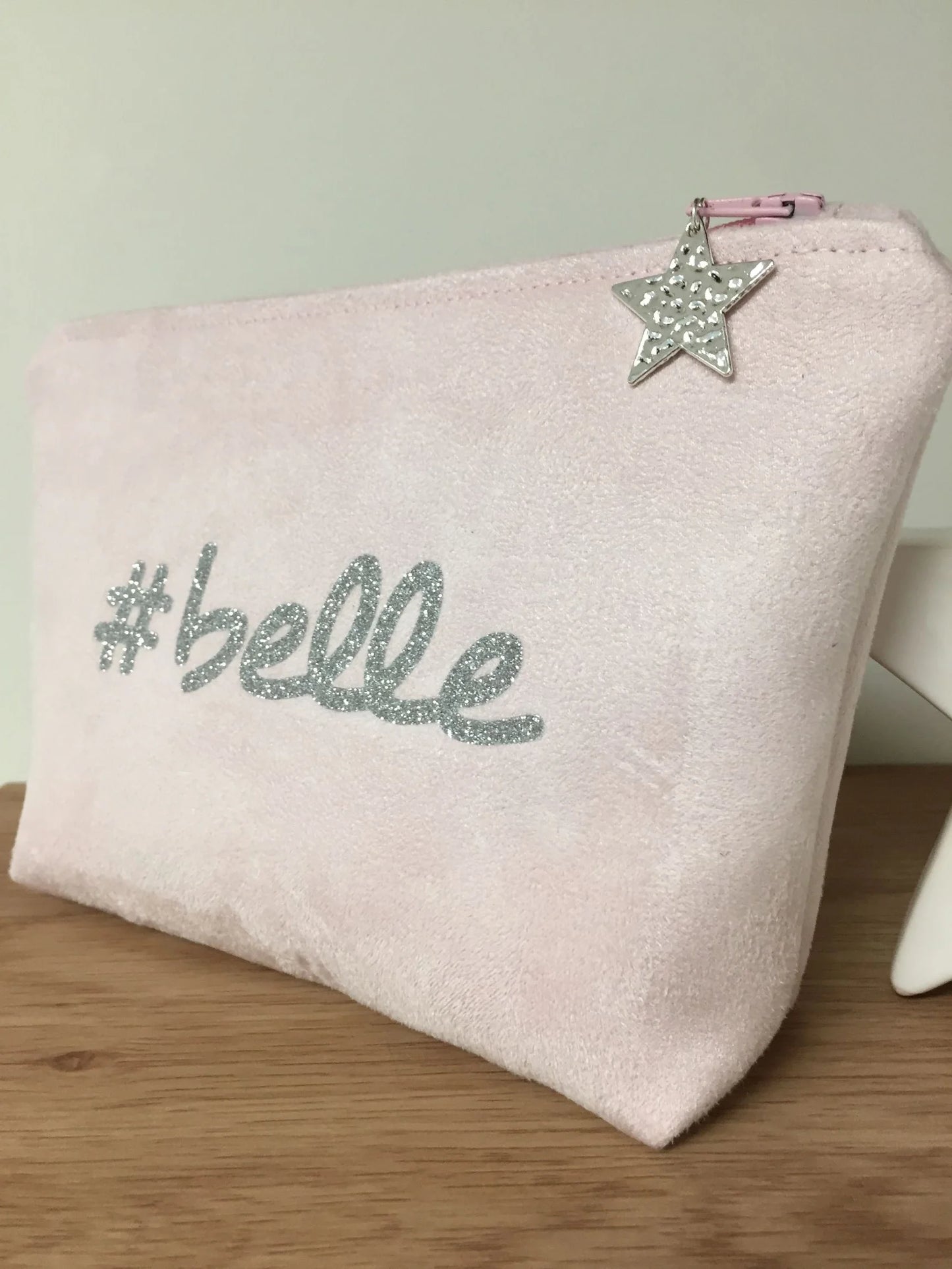 La face avant de la pochette à maquillage rose pastel belle à paillettes argentées.