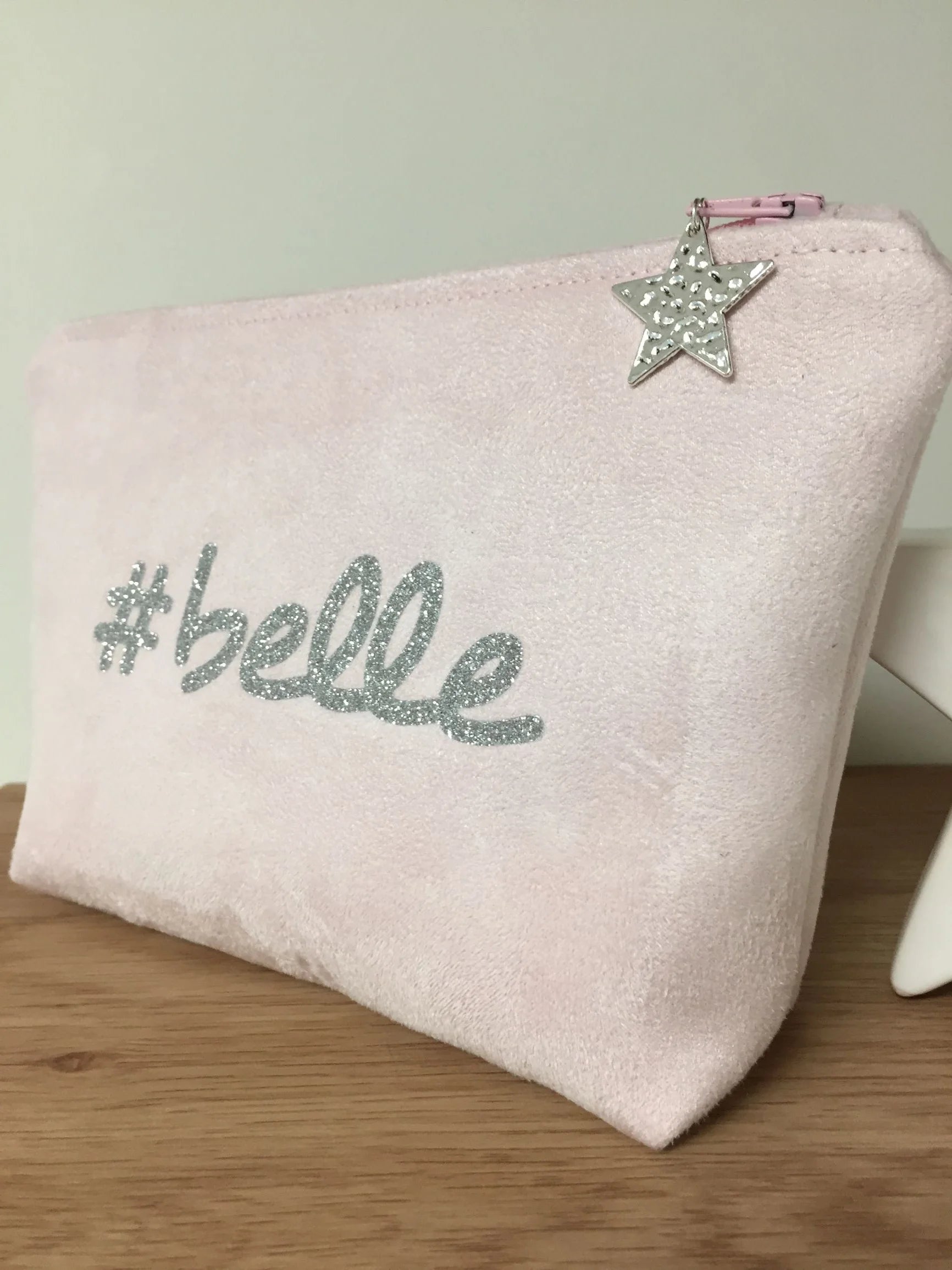 La face avant de la pochette à maquillage rose pastel belle à paillettes argentées.