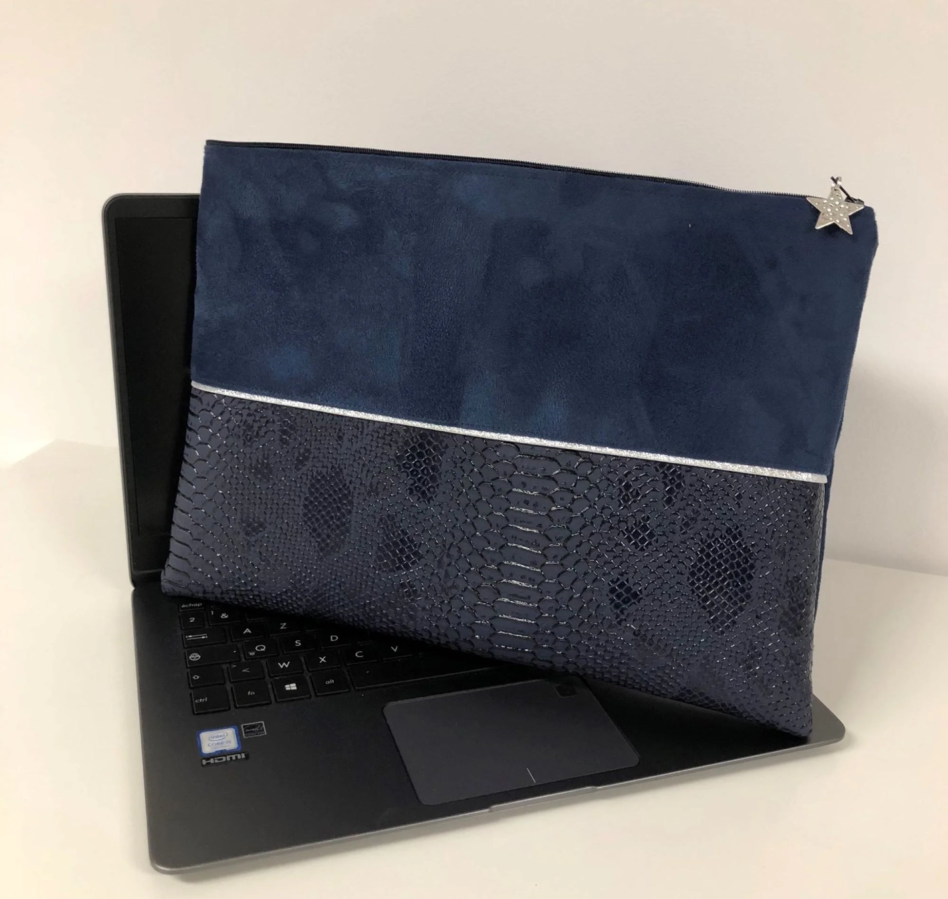 La pochette ordinateur bleu marine et argentée aspect reptile, posée sur un PC Asus.