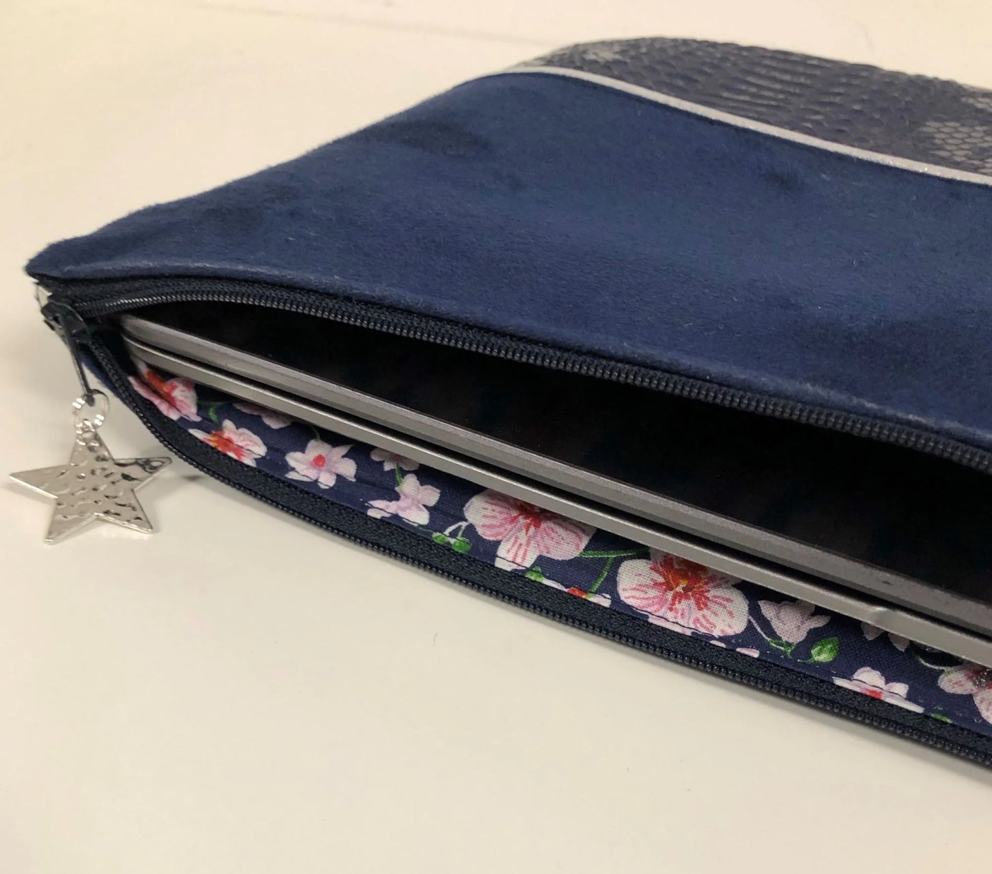 La pochette ordinateur bleu marine et argentée aspect reptile, avec ordinateur à l'intérieur.