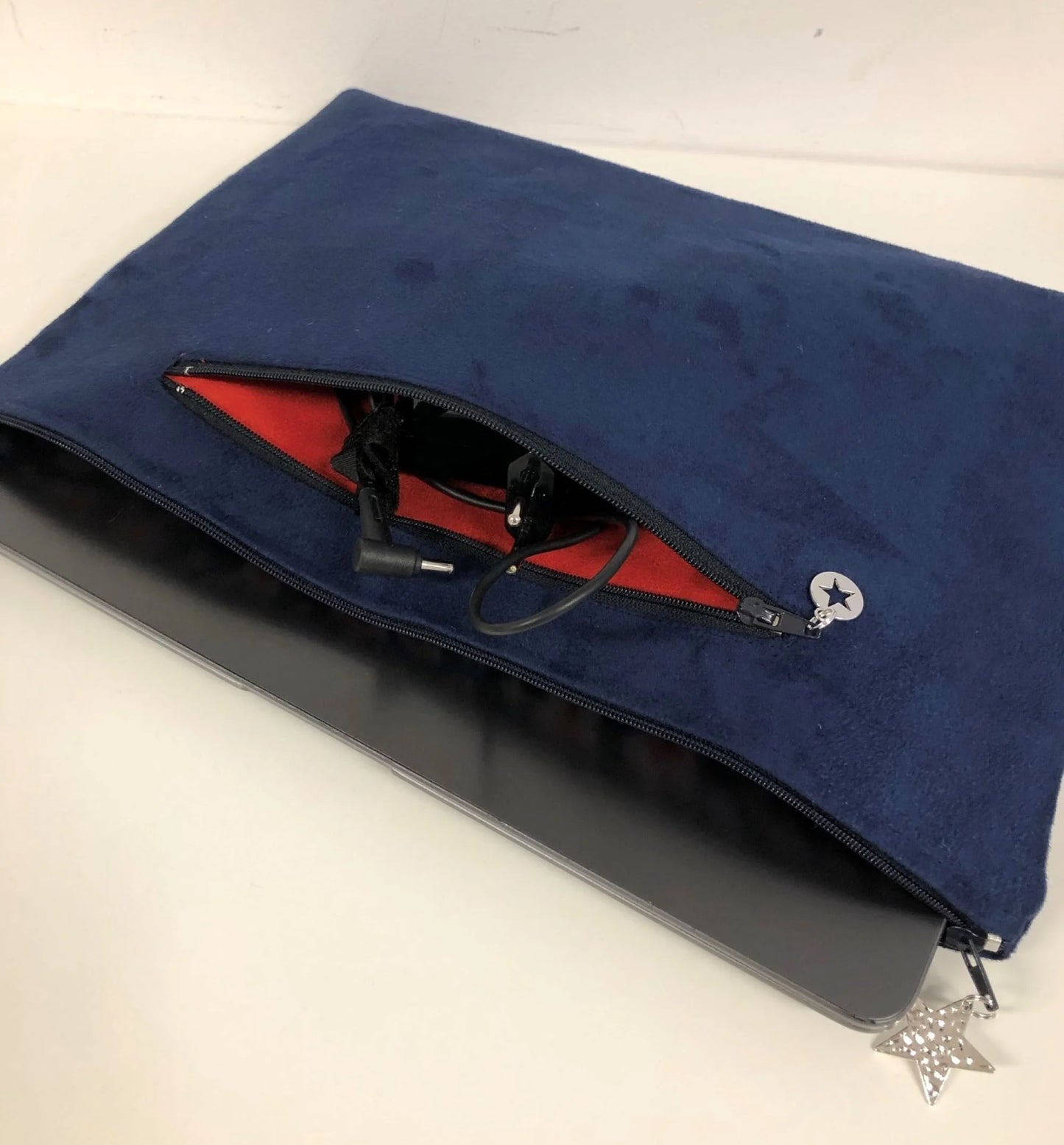 La pochette ordinateur bleu marine et argentée aspect reptile, poche chargeur à l'arrière.