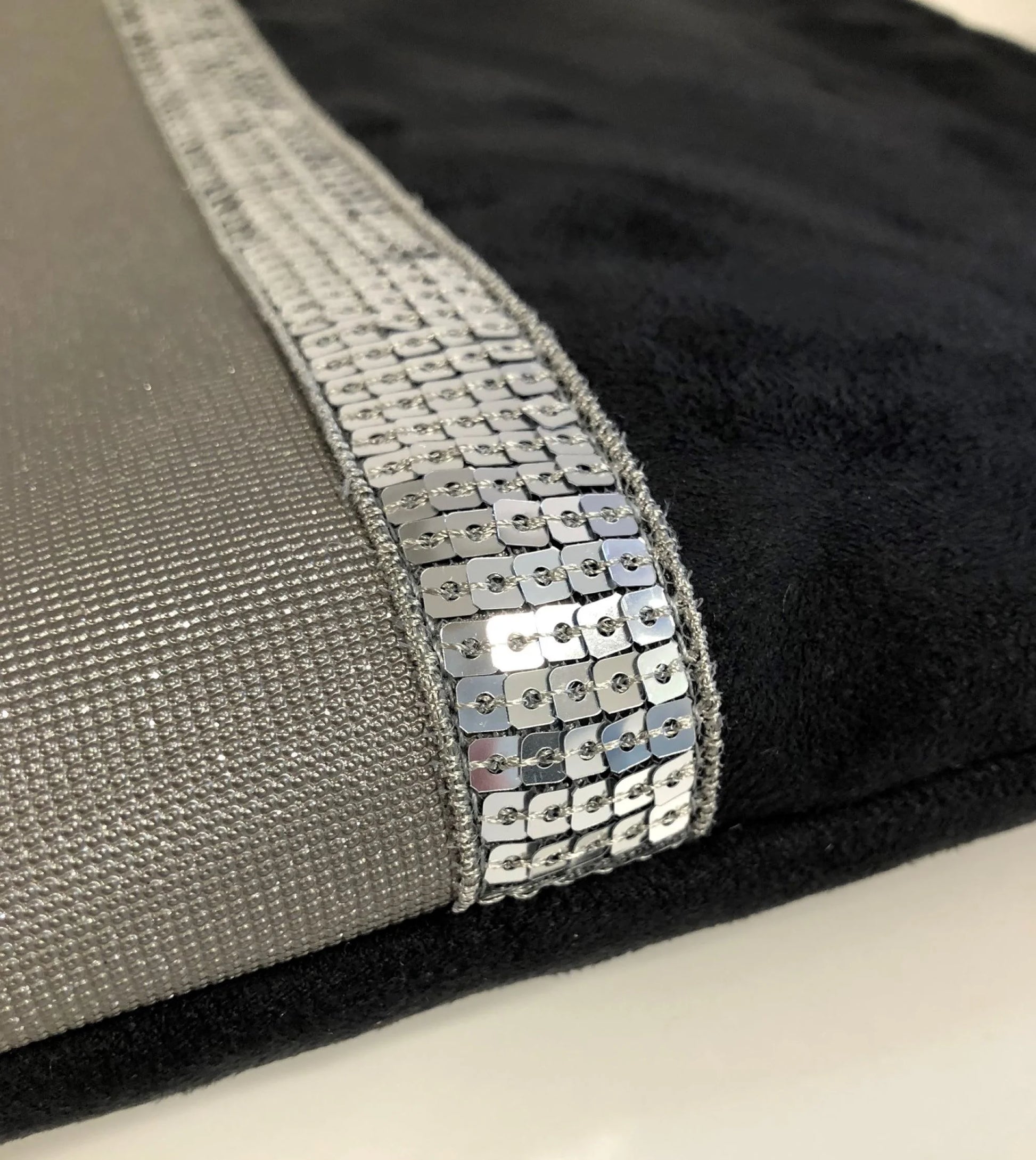 Vue détaillée de la face avant de la pochette ordinateur noir et gris à paillettes argentées.