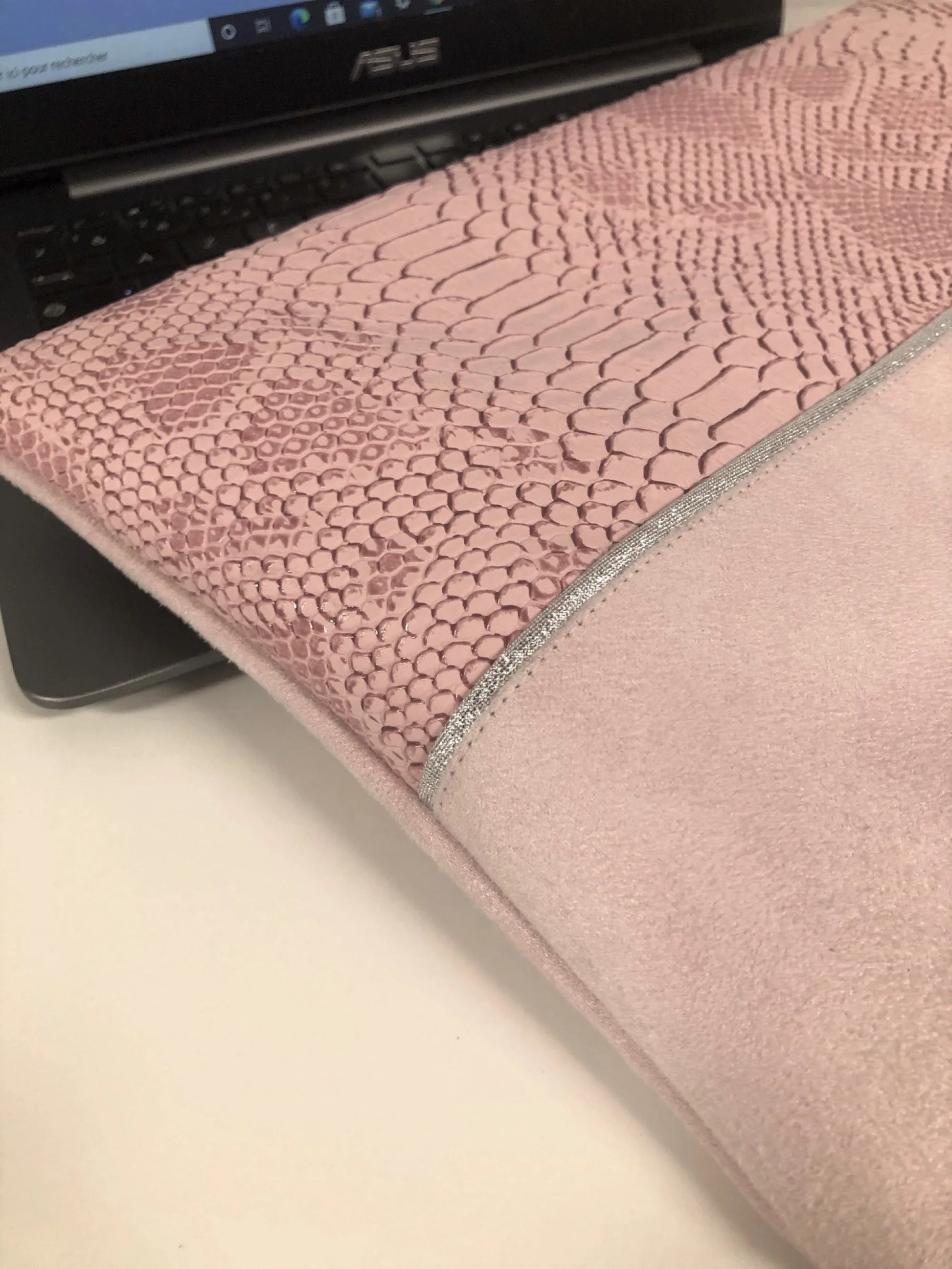Vue détaillée de la face avant de la pochette ordinateur rose pâle et argentée aspect reptile.