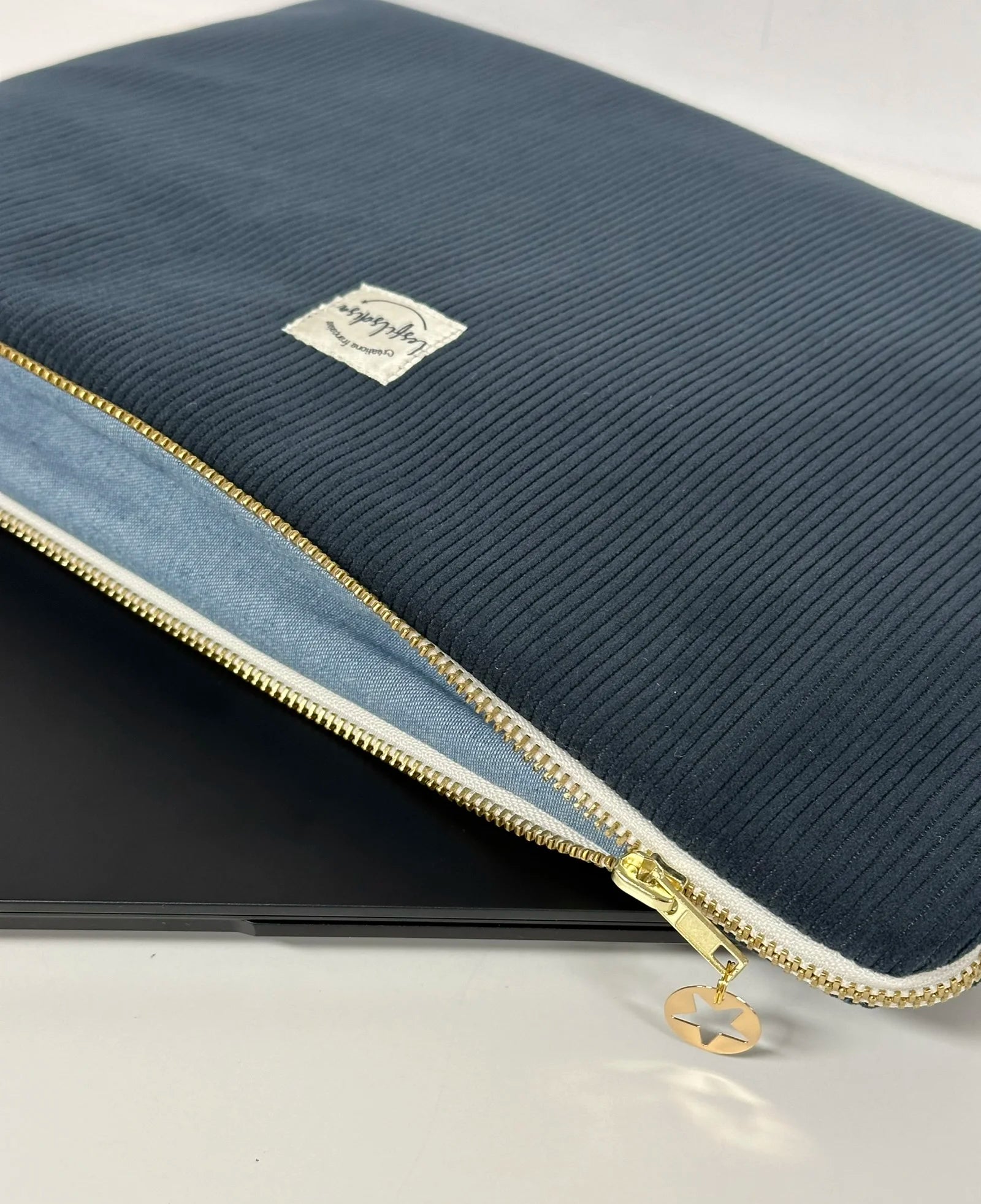 La pochette ordinateur en velours cotelé bleu canard, entrouverte.