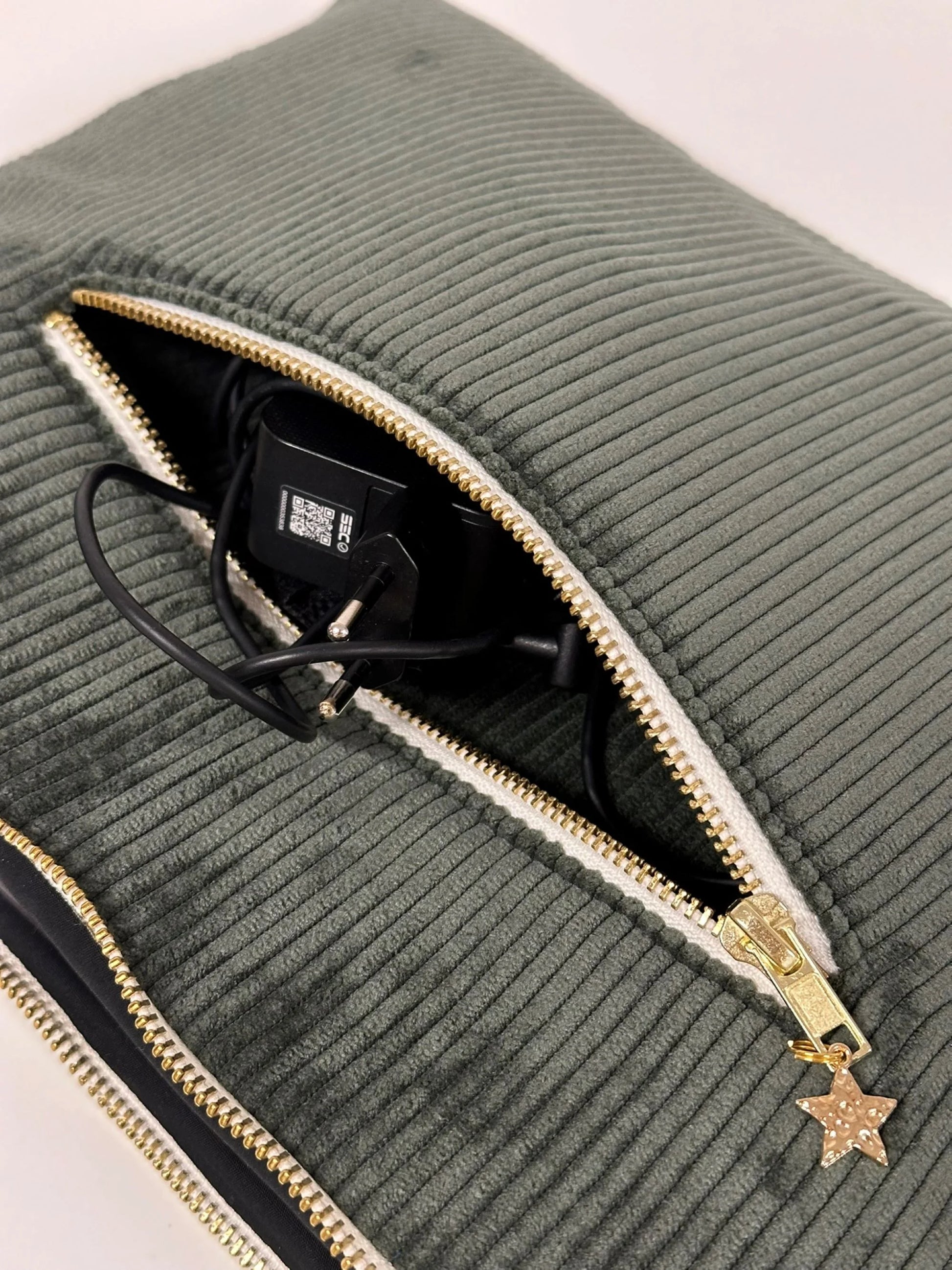 Le chargeur dans la poche arrière de la pochette ordinateur en velours cotelé vert kaki.