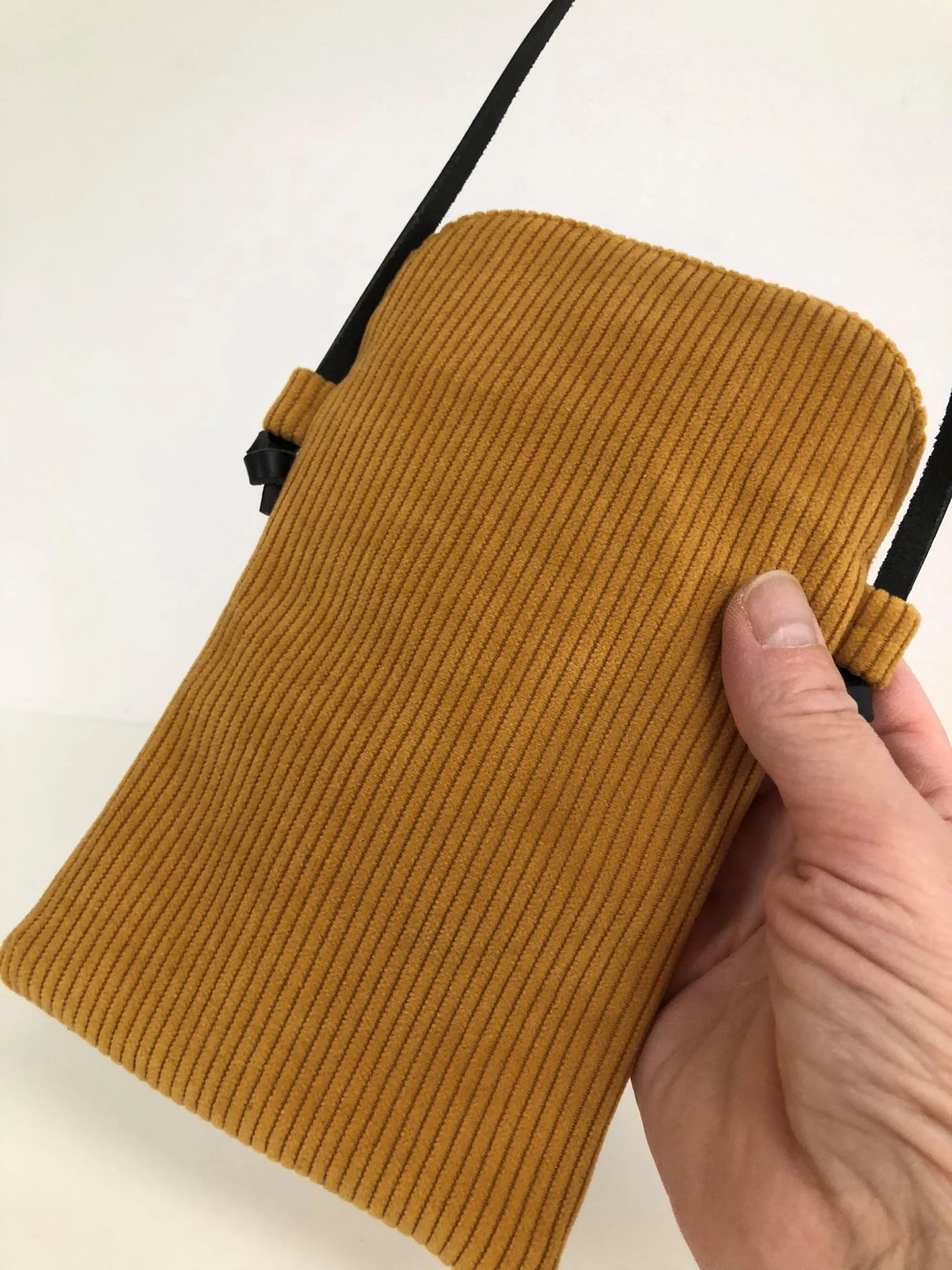 Le dos de la pochette téléphone bandoulière en velours cotelé jaune moutarde.