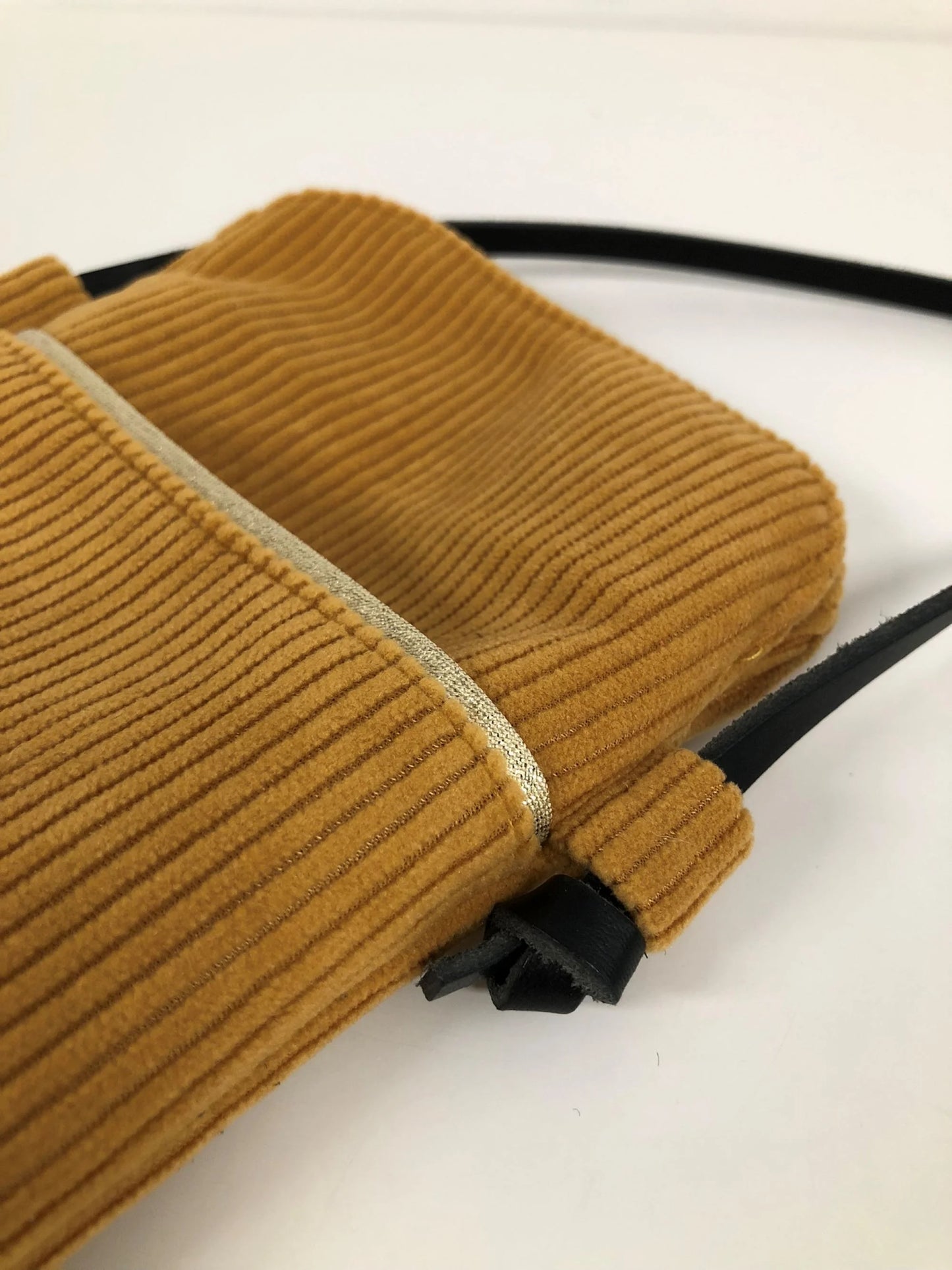 La pochette téléphone bandoulière en velours cotelé jaune moutarde et cuir noir.