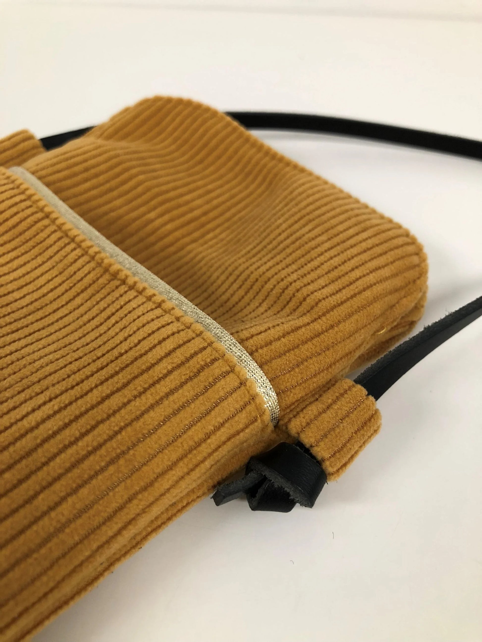 La pochette téléphone bandoulière en velours cotelé jaune moutarde et cuir noir.