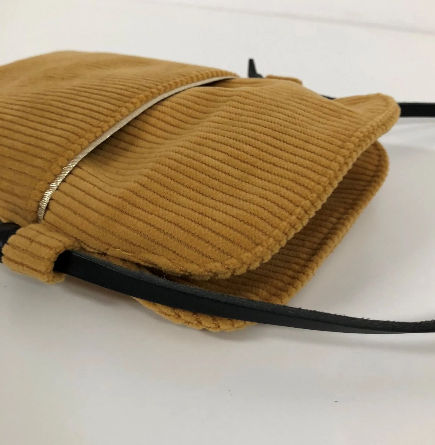 La poche avant de la pochette téléphone bandoulière en velours cotelé jaune moutarde.
