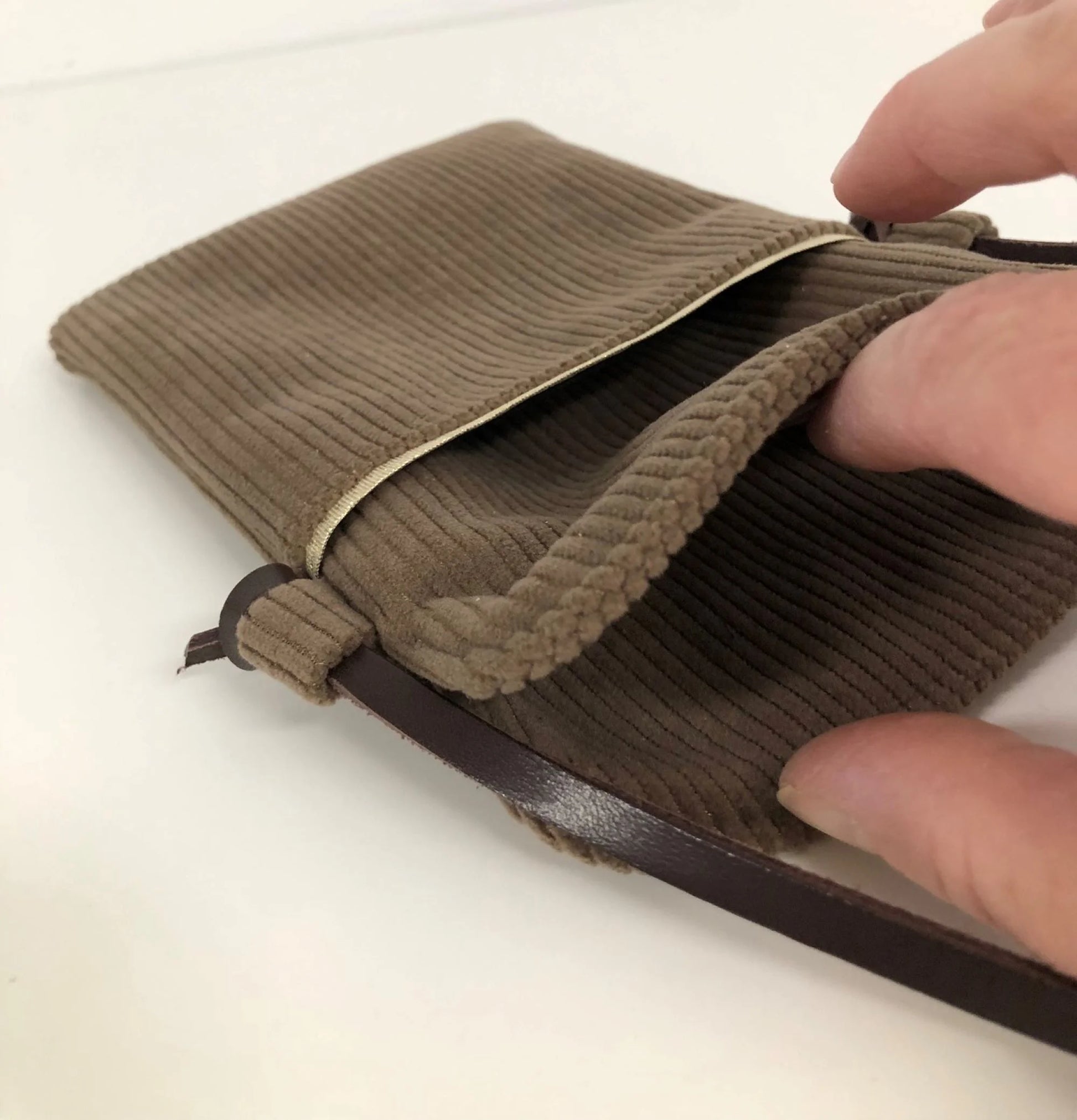 L'intérieur de la pochette téléphone bandoulière en velours cotelé marron chamois et cuir.