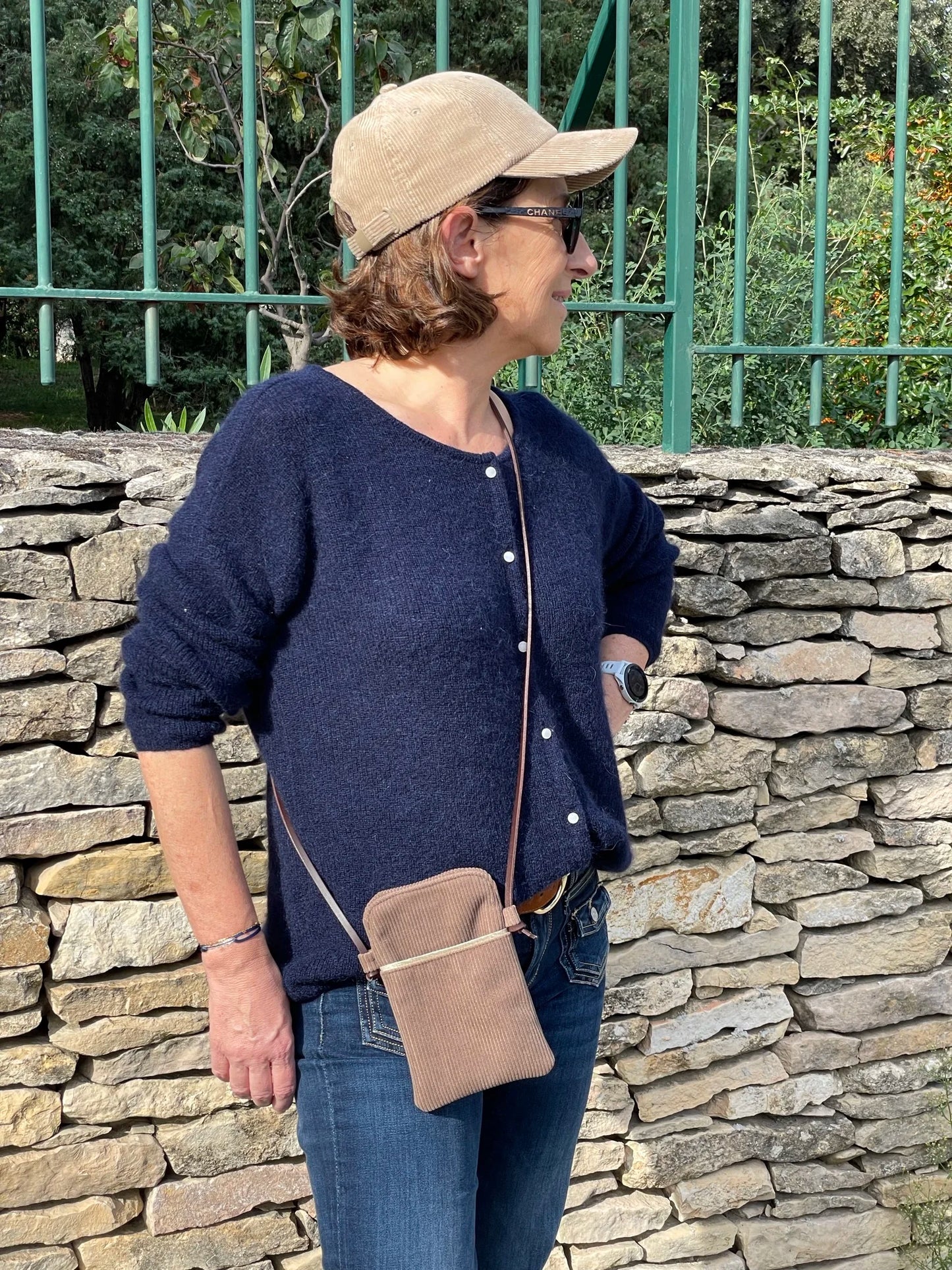 La pochette téléphone bandoulière en velours côtelé beige et cuir , portée en travers
