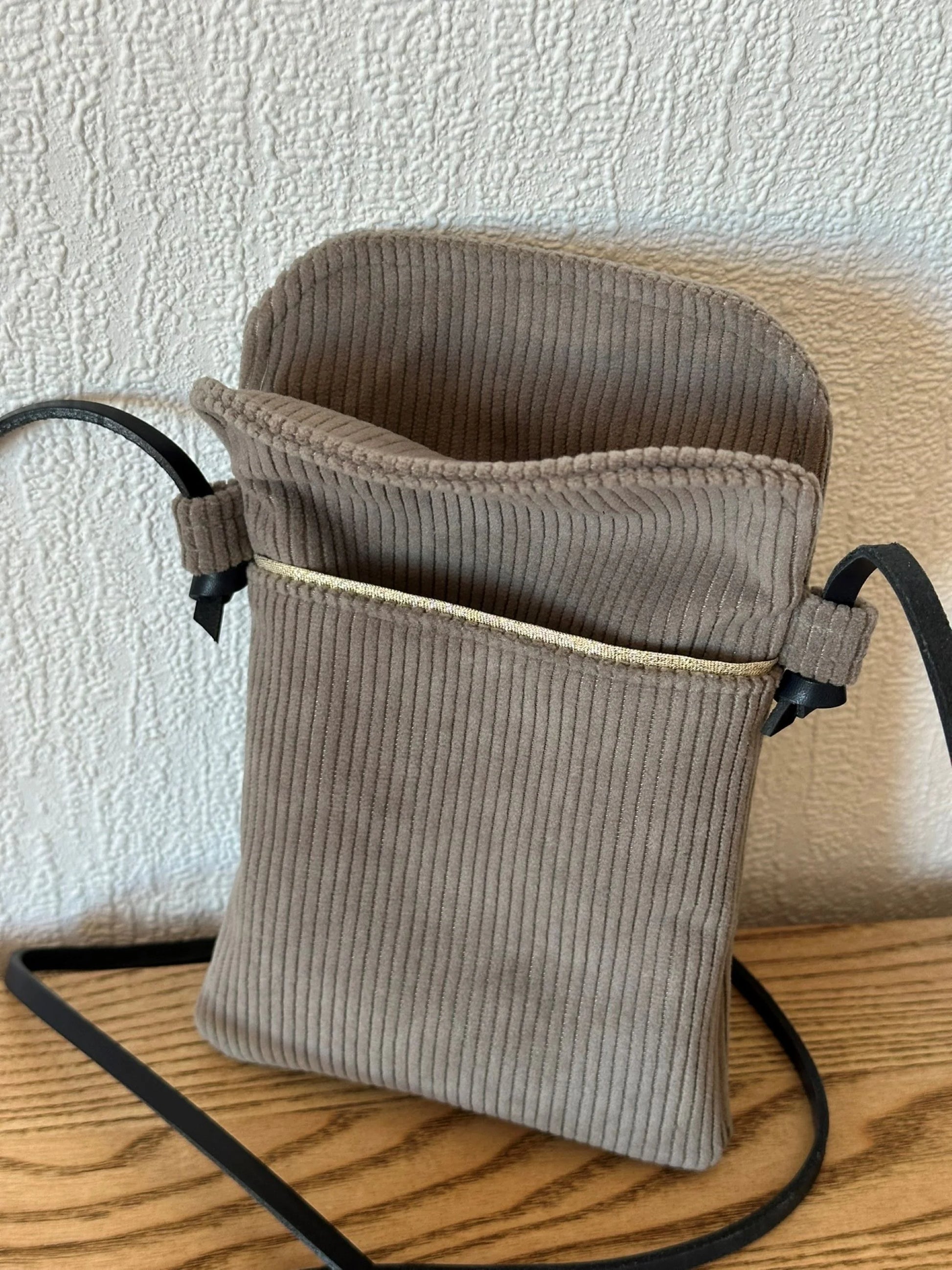 L'ouverture de la pochette téléphone en velours cotelé taupe .