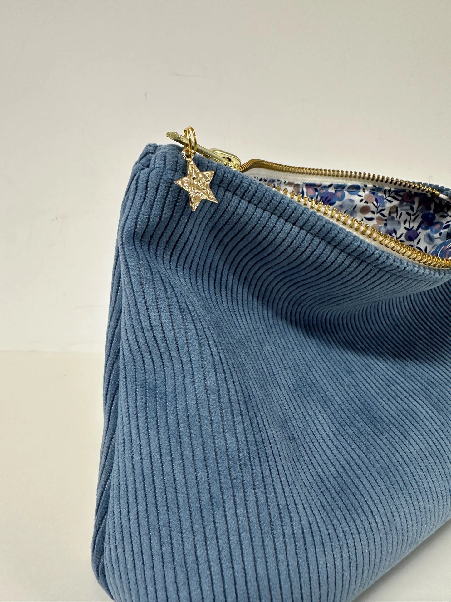La pochette en velours côtelé bleu azur et son zip métal doré