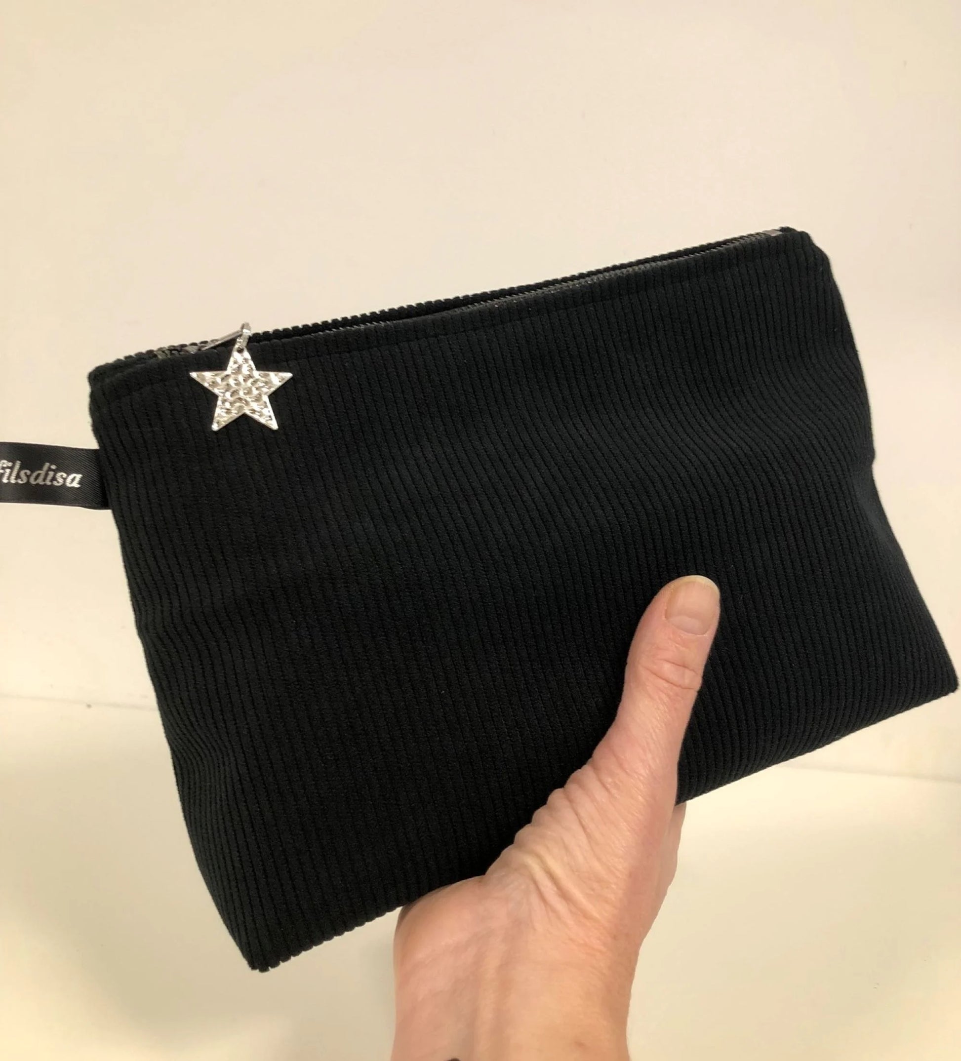 La pochette en velours côtelé noir fermée