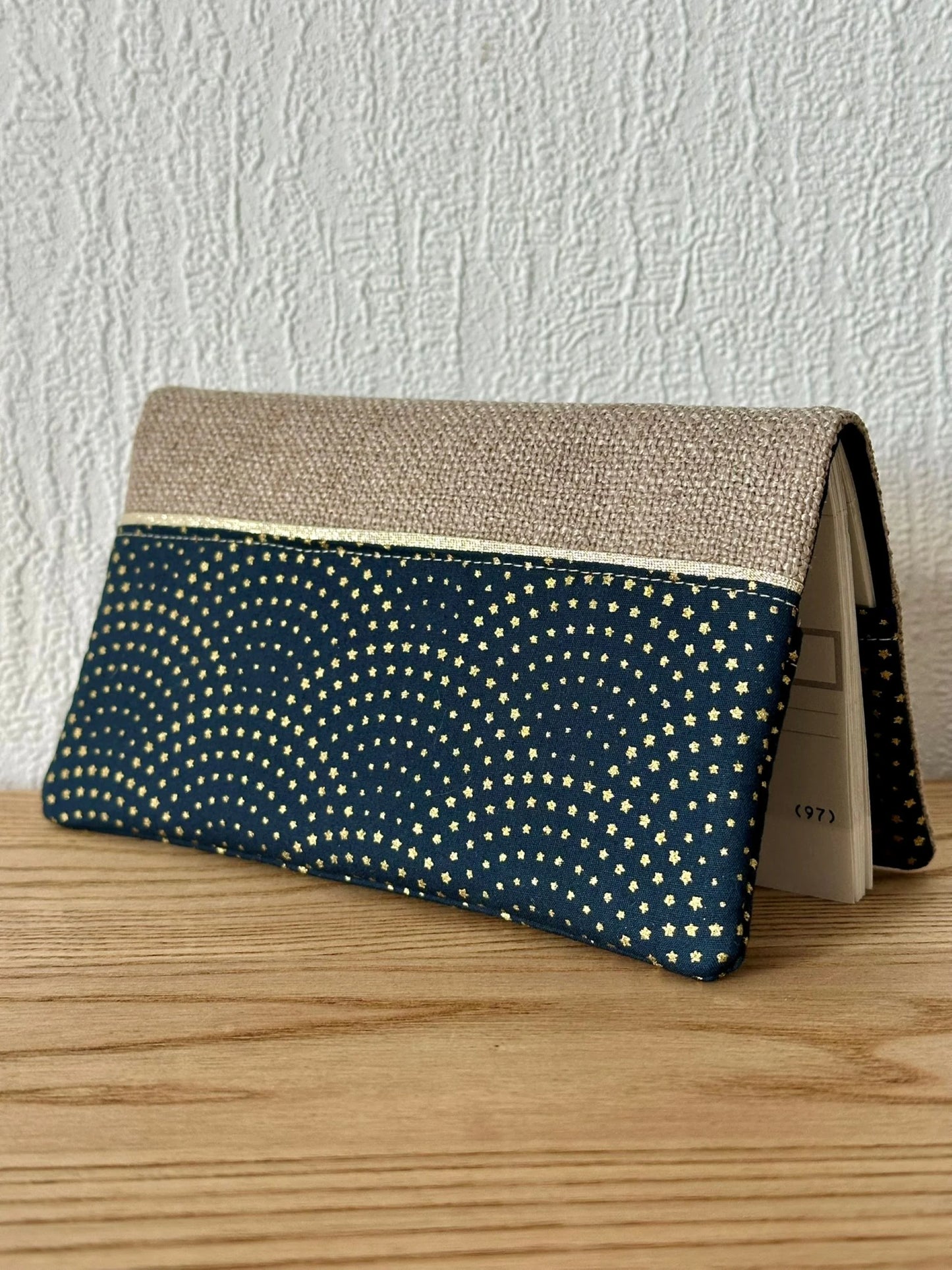 Face avant du porte chéquier beige et bleu à étoiles dorées.